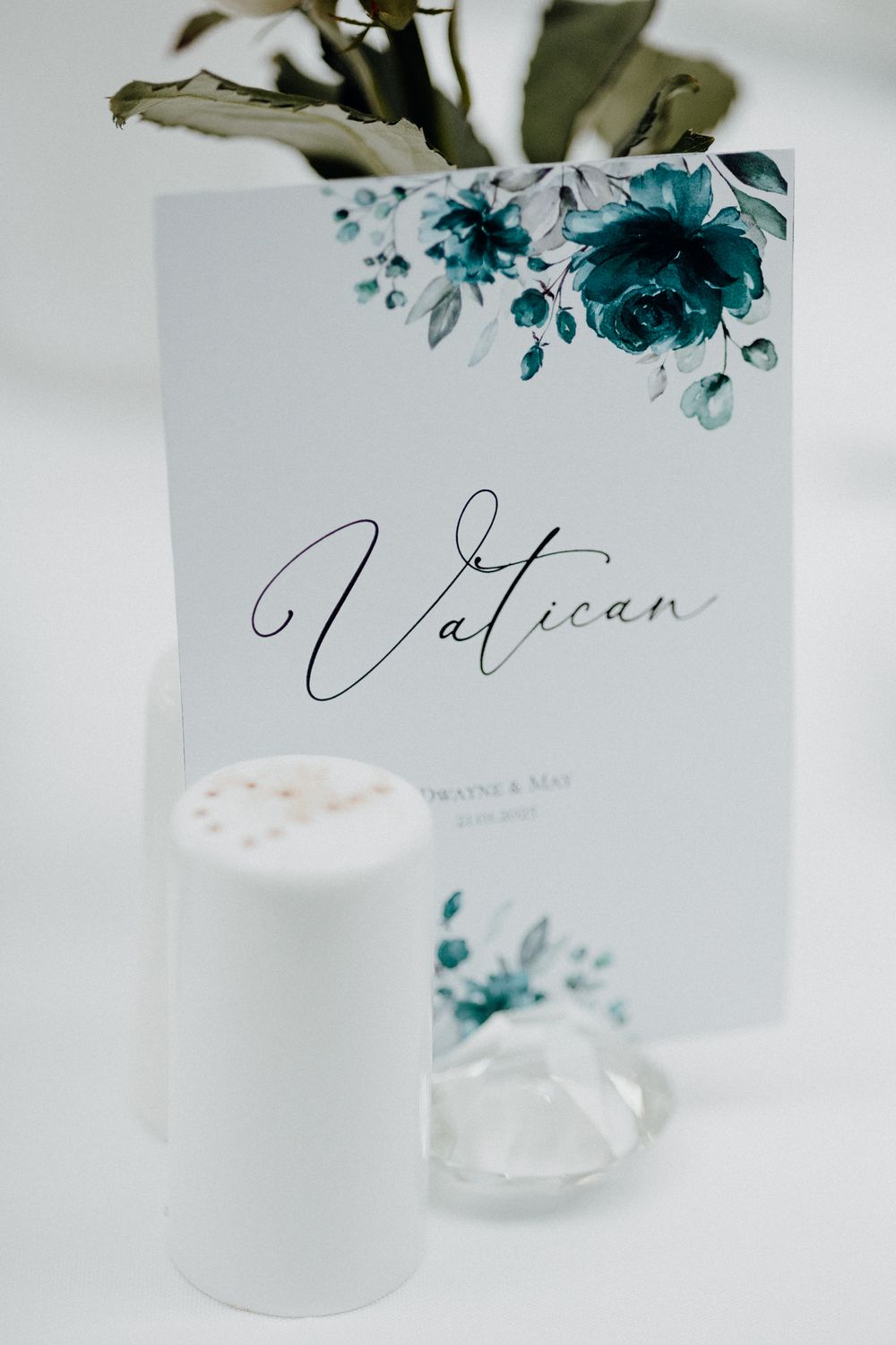 A wedding name card with teal floral design and elegant calligraphy captured by Apertured Media Auckland Wedding Photographer