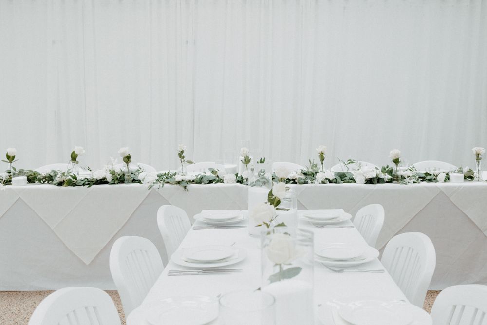 White wedding reception table setting with elegant place settings captured by Apertured Media Auckland Wedding Photographer