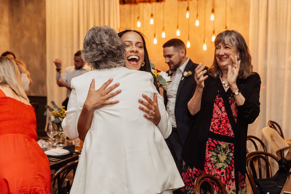 Emotional celebration moment with guests embracing and laughing at an indoor event.