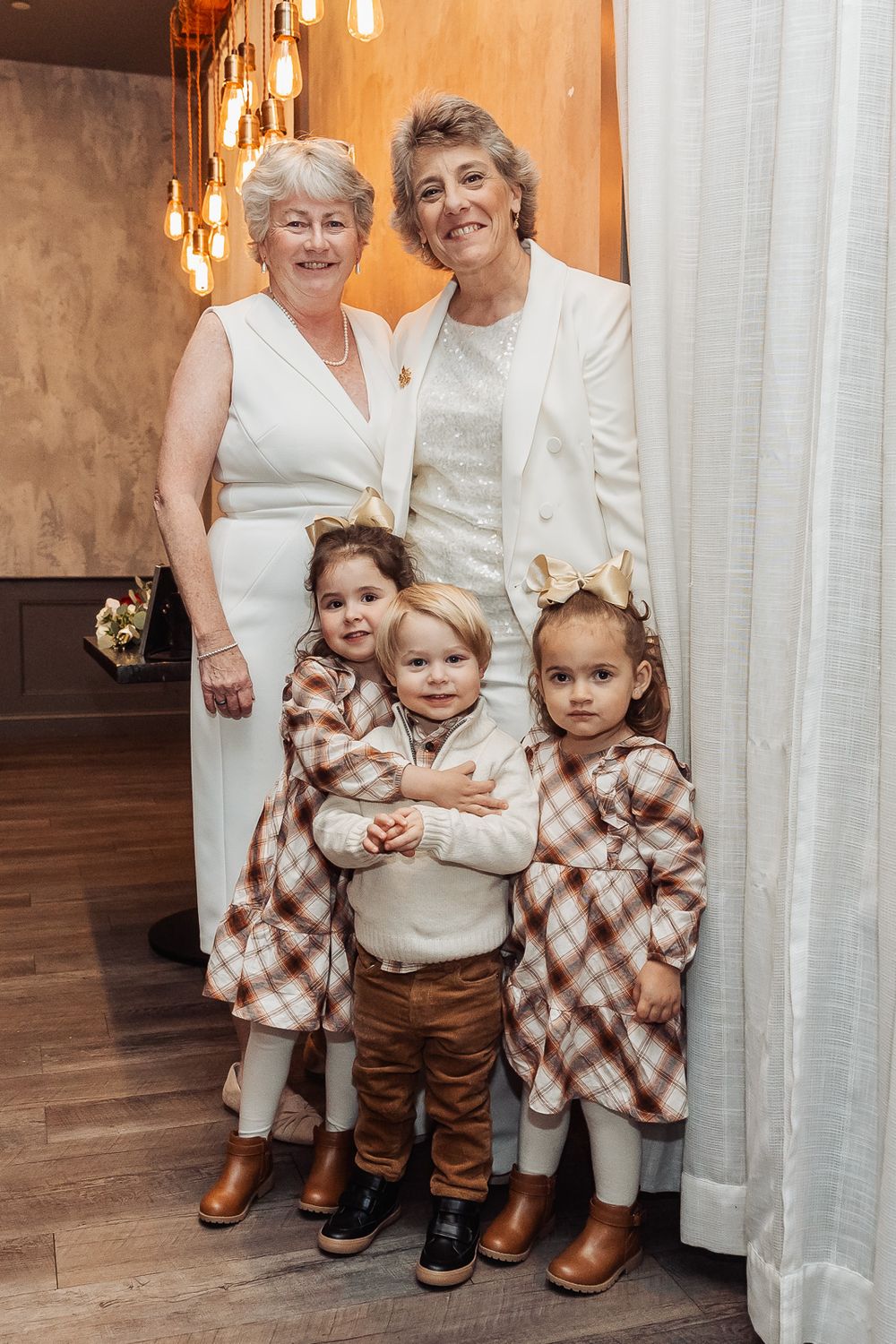 Family portrait of adults and children in coordinated white and plaid outfits.