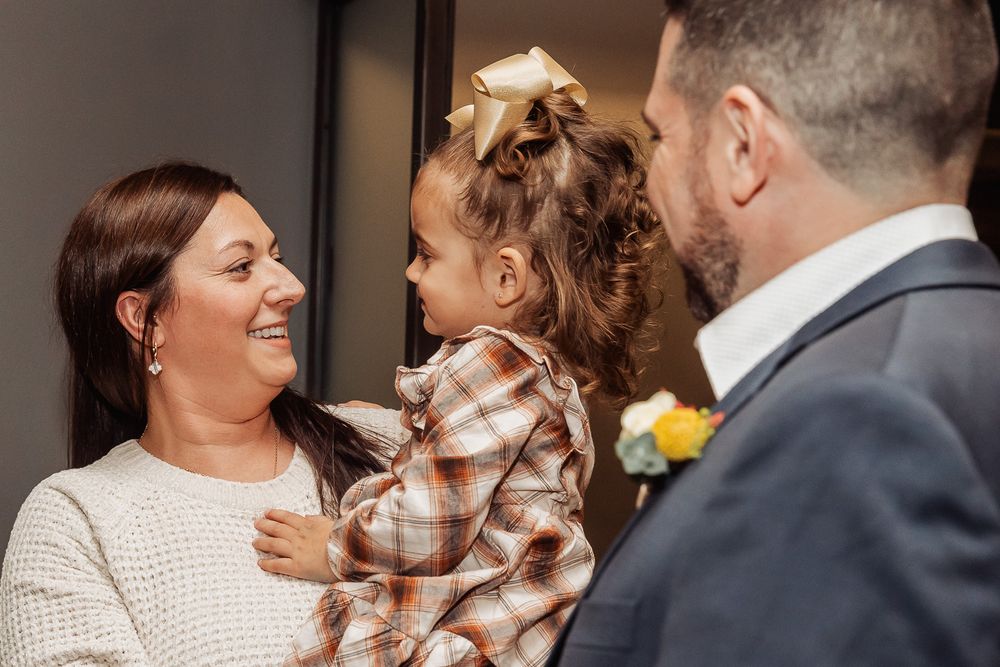 Candid moment between guests and child in plaid dress at formal event.