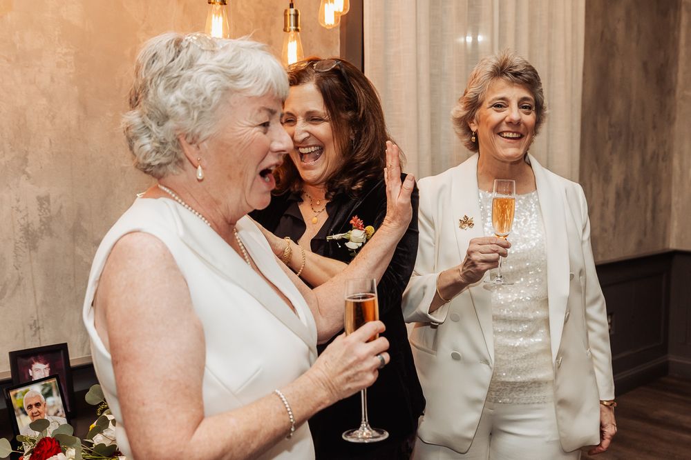 Guests celebrating with champagne at an elegant event with pendant lighting and textured walls.