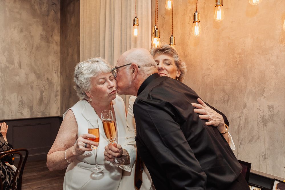 Friends sharing an intimate moment at a celebration with warm lighting and champagne.