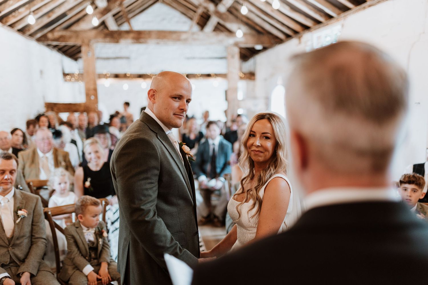 A joyful couple exchanges vows during their rustic barn wedding ceremony surrounded by guests at Stanford Farm, Shrewsbury.