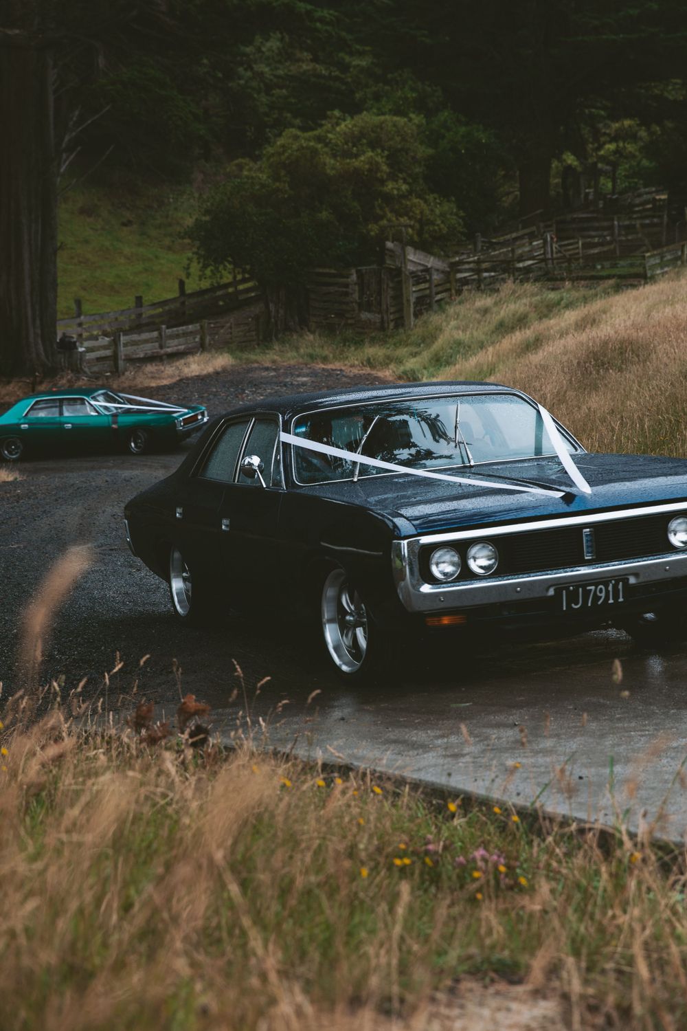 Vintage black classic cars parked on a winding hillside road.