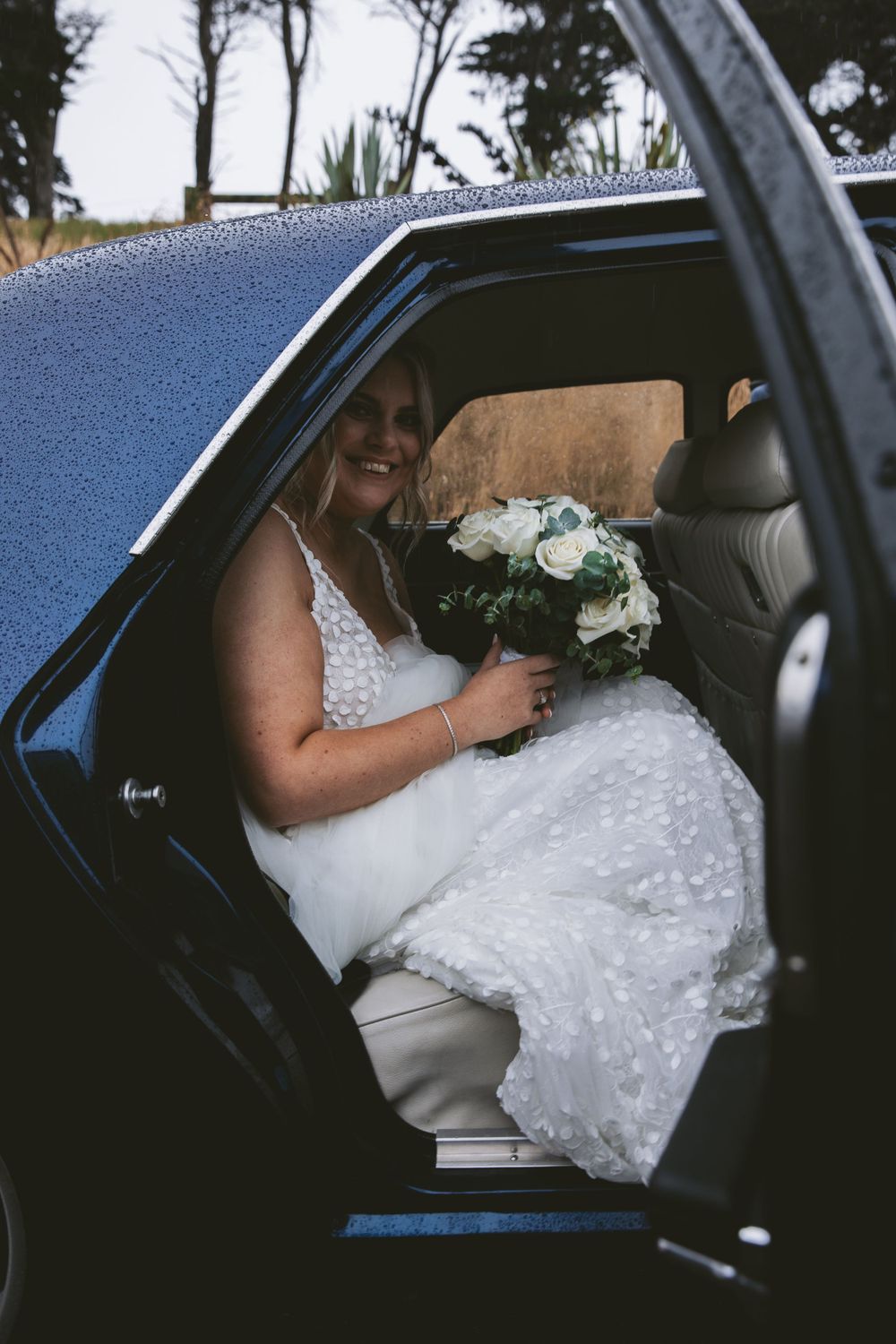 White floral bouquet in classic car on wedding day.