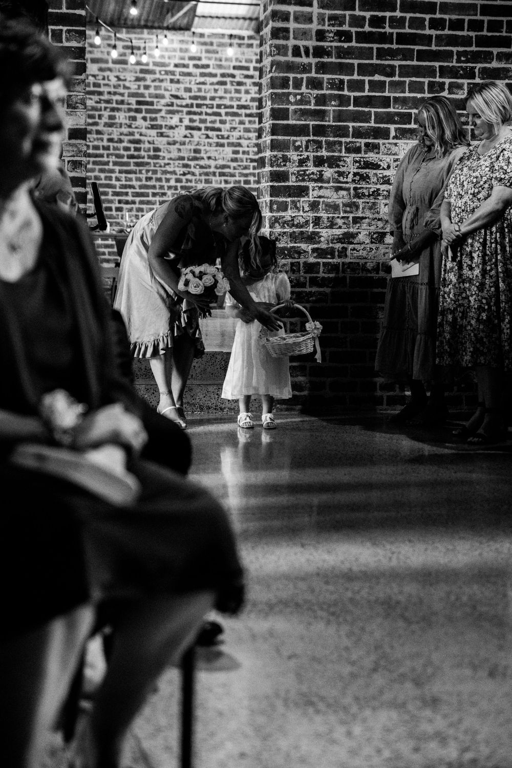 A black and white wedding reception scene shows a young child dancing in front of wedding guests.
