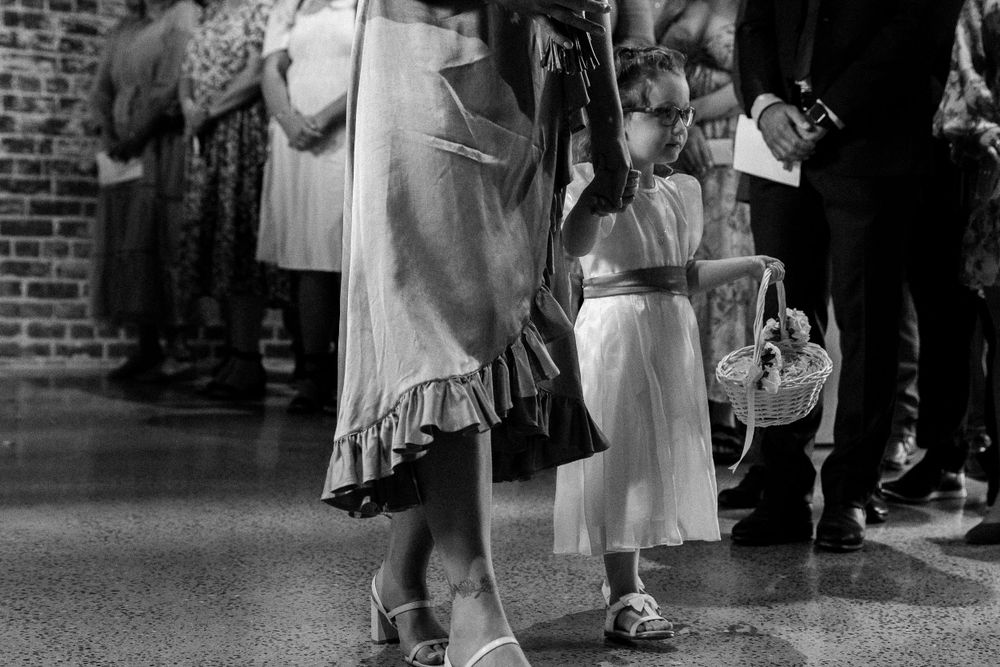 Black and white photo of wedding guests' feet and dresses on a dance floor against exposed brick walls.