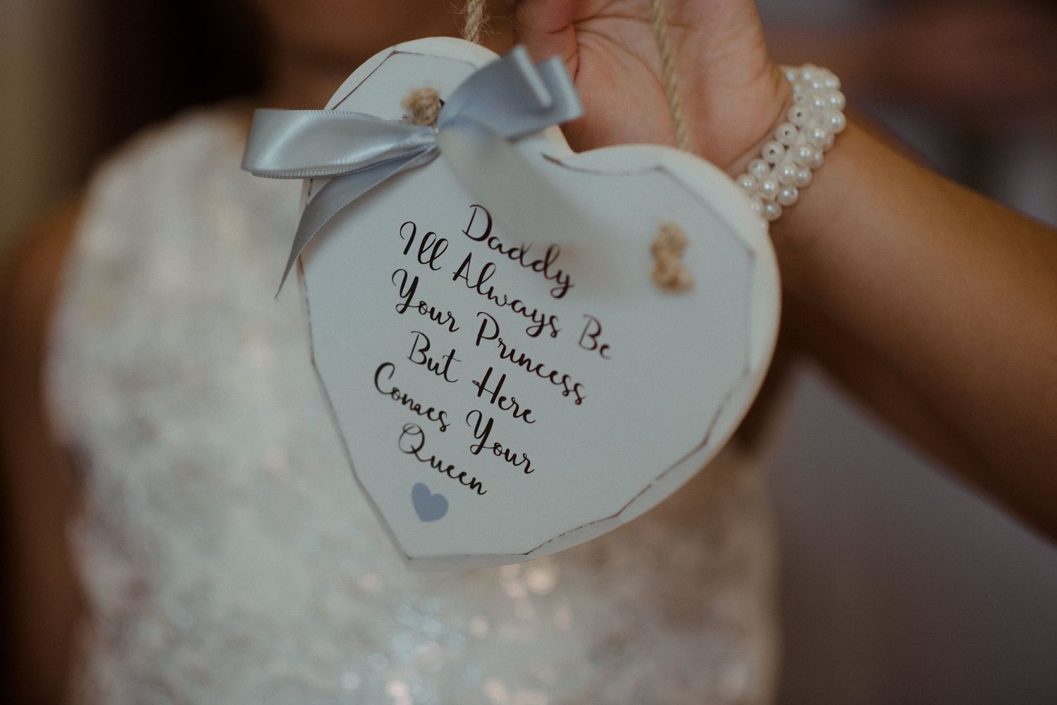 Close up of a heart-shaped note with handwritten message and blue ribbon.
