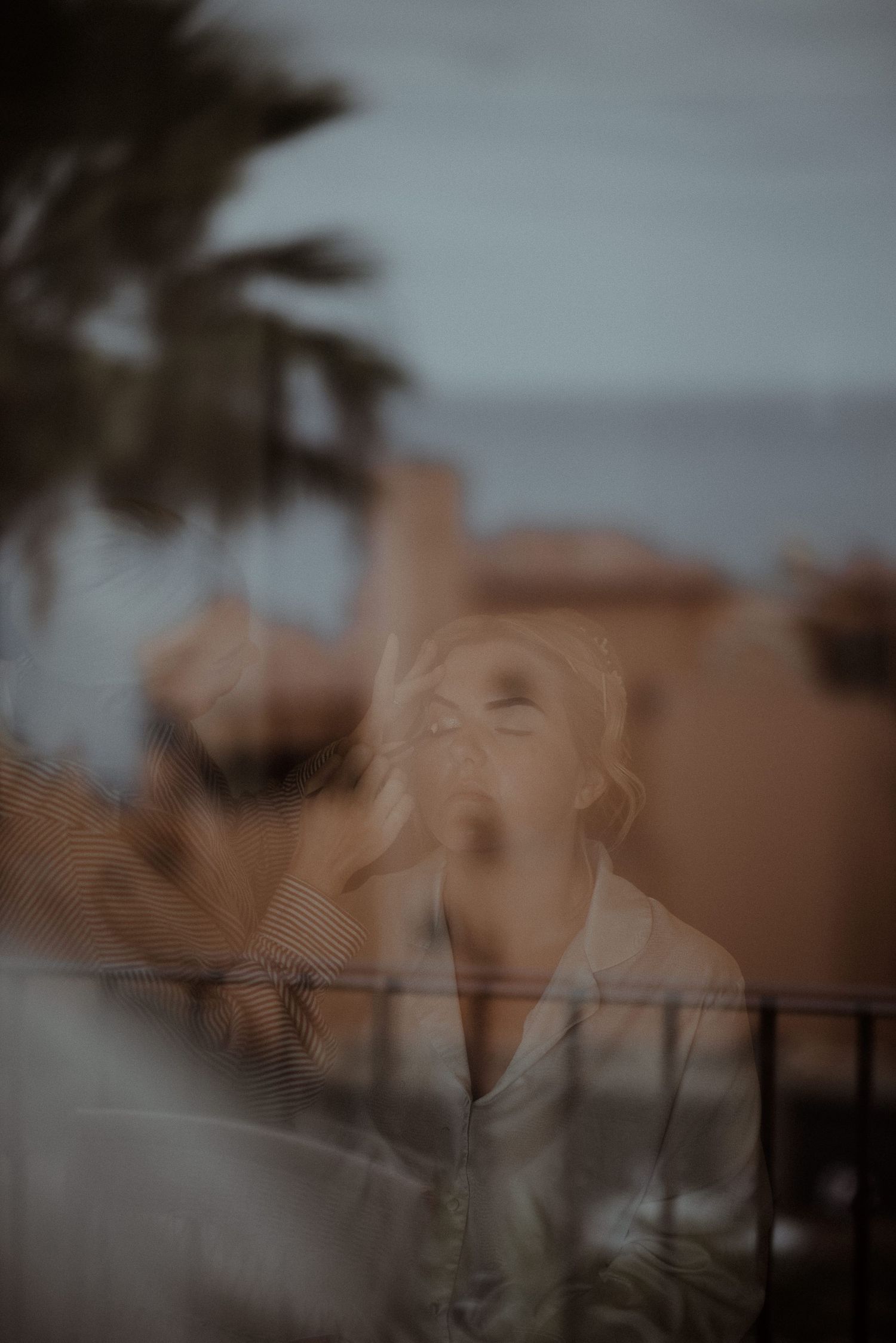 Artistic double exposure portrait with palm trees and architecture.