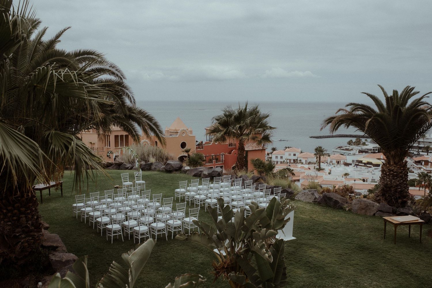 Outdoor wedding ceremony setup with white chairs overlooking an oceanfront view.