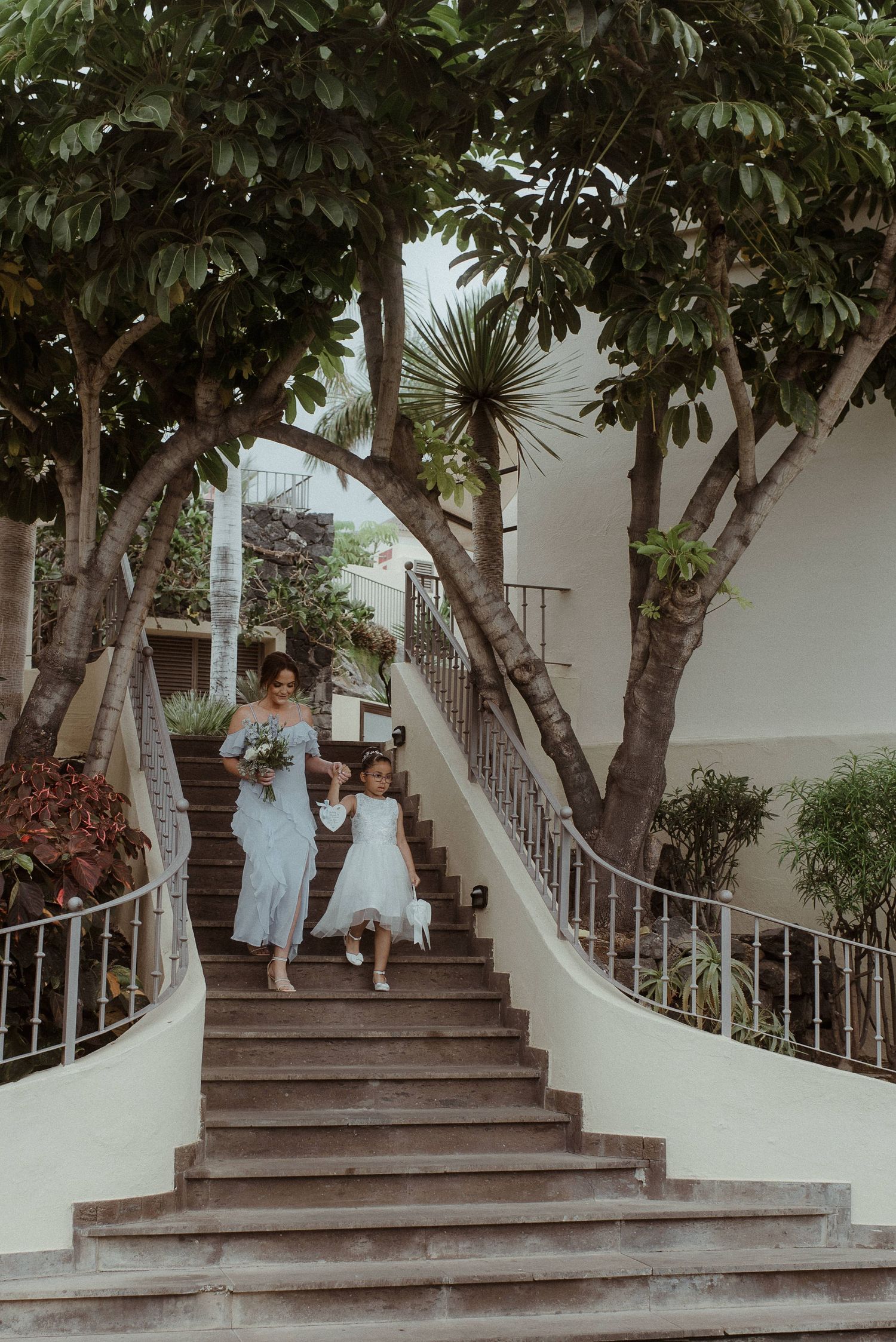Two people walking down a curved white staircase during a wedding celebration.