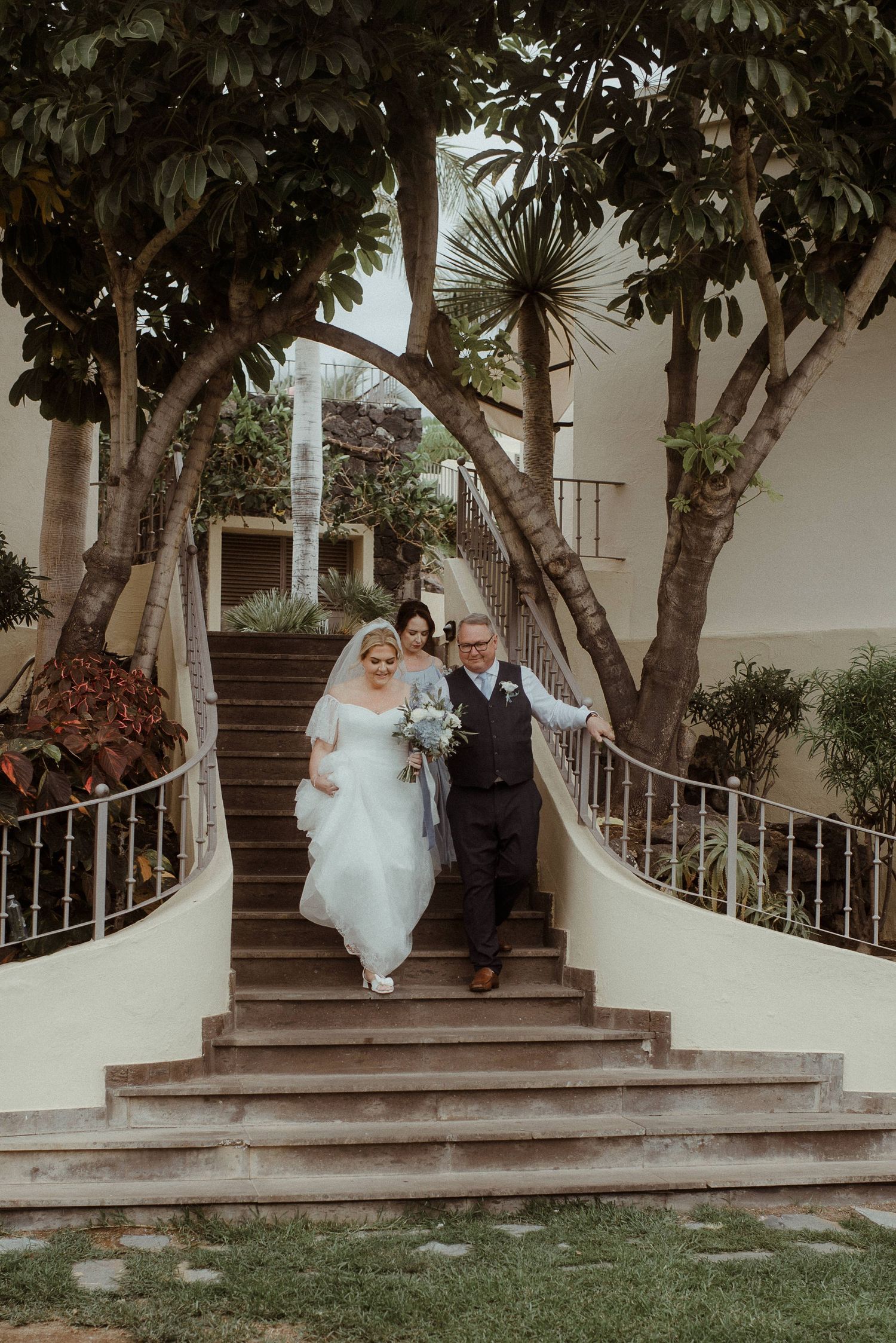 A couple descends an elegant outdoor staircase surrounded by tropical greenery. Tenerife Wedding Photographer at Hotel Vincci La Plantación