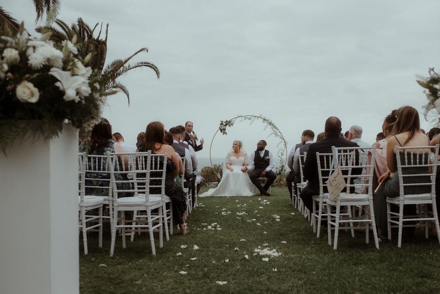 Outdoor wedding ceremony setup with white chairs and floral arch overlooking a scenic view. Tenerife Wedding Photographer at Hotel Vincci