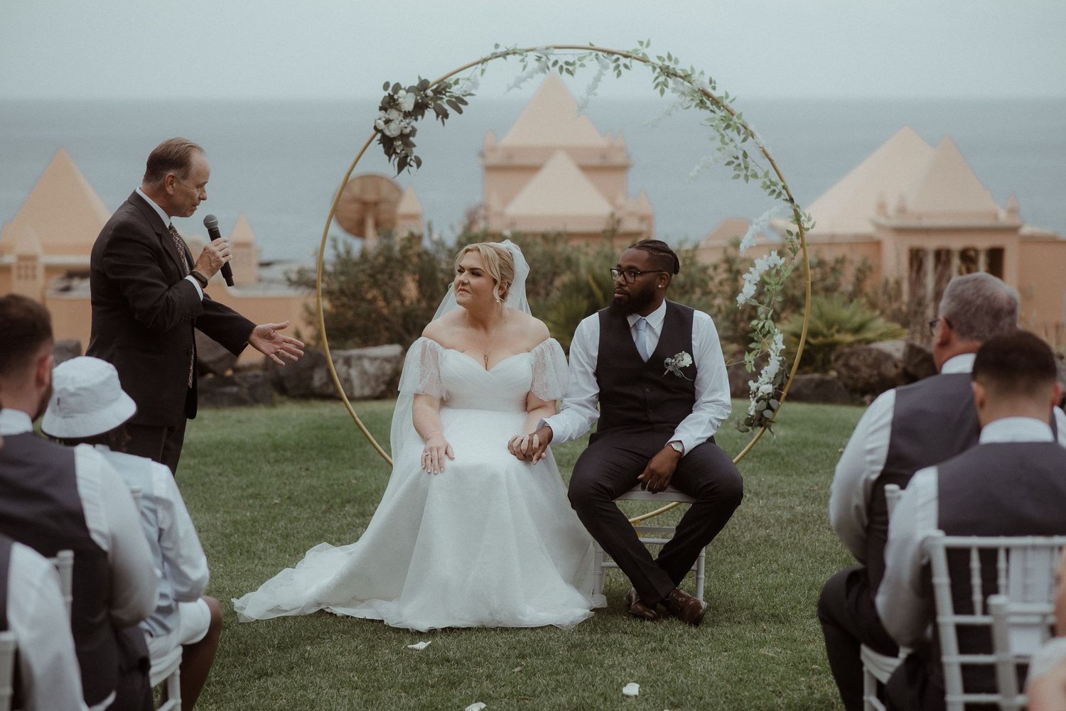 Wedding ceremony on a grassy hillside with coastal views and decorated arch. Tenerife Wedding Photographer at Hotel Vincci La Plantación