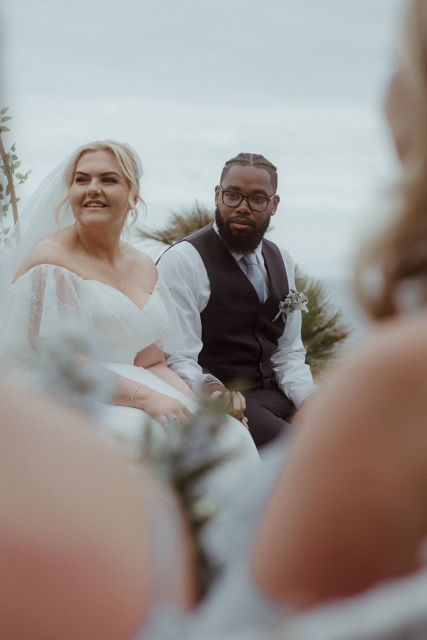 Candid ceremony moment under floral arch with blurred foreground. Tenerife Wedding Photographer at Hotel Vincci La Plantación del Sur