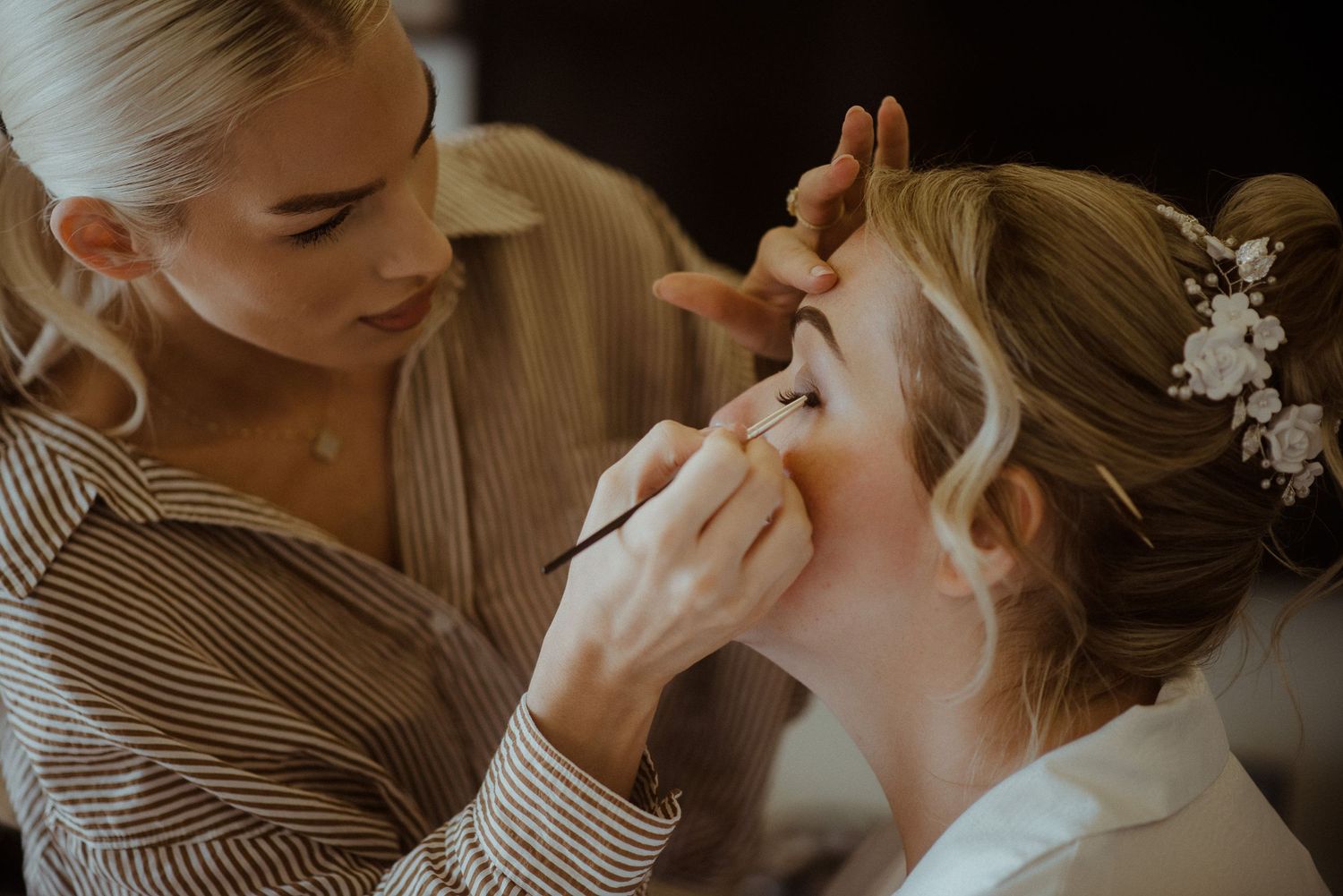 Professional makeup artist applying eye makeup in warm lighting. Tenerife Wedding Photographer at Hotel Vincci La Plantación del Sur