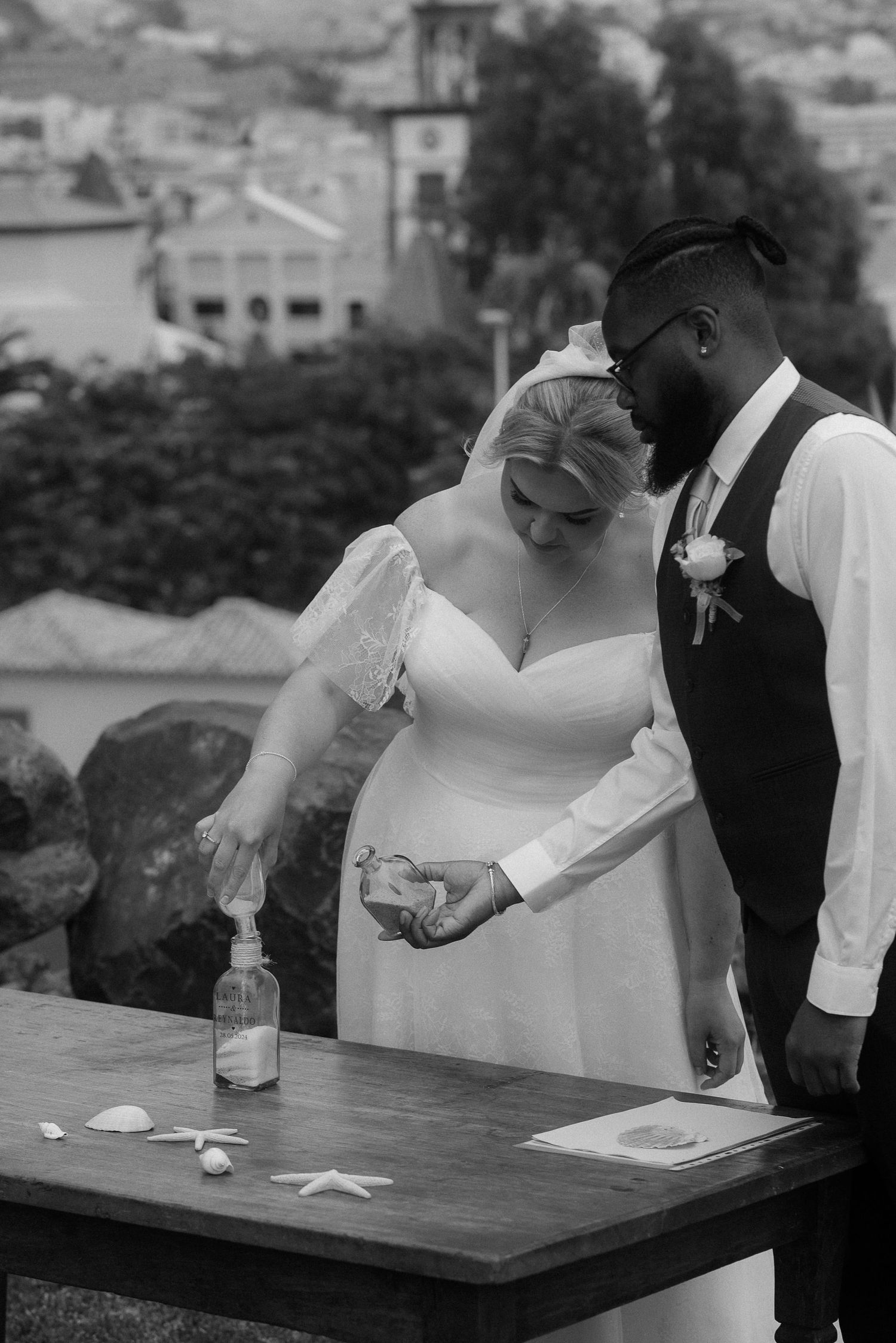 Black and white photo of a couple performing a ceremony ritual at an outdoor table. Tenerife Wedding Photographer at Hotel Vincci