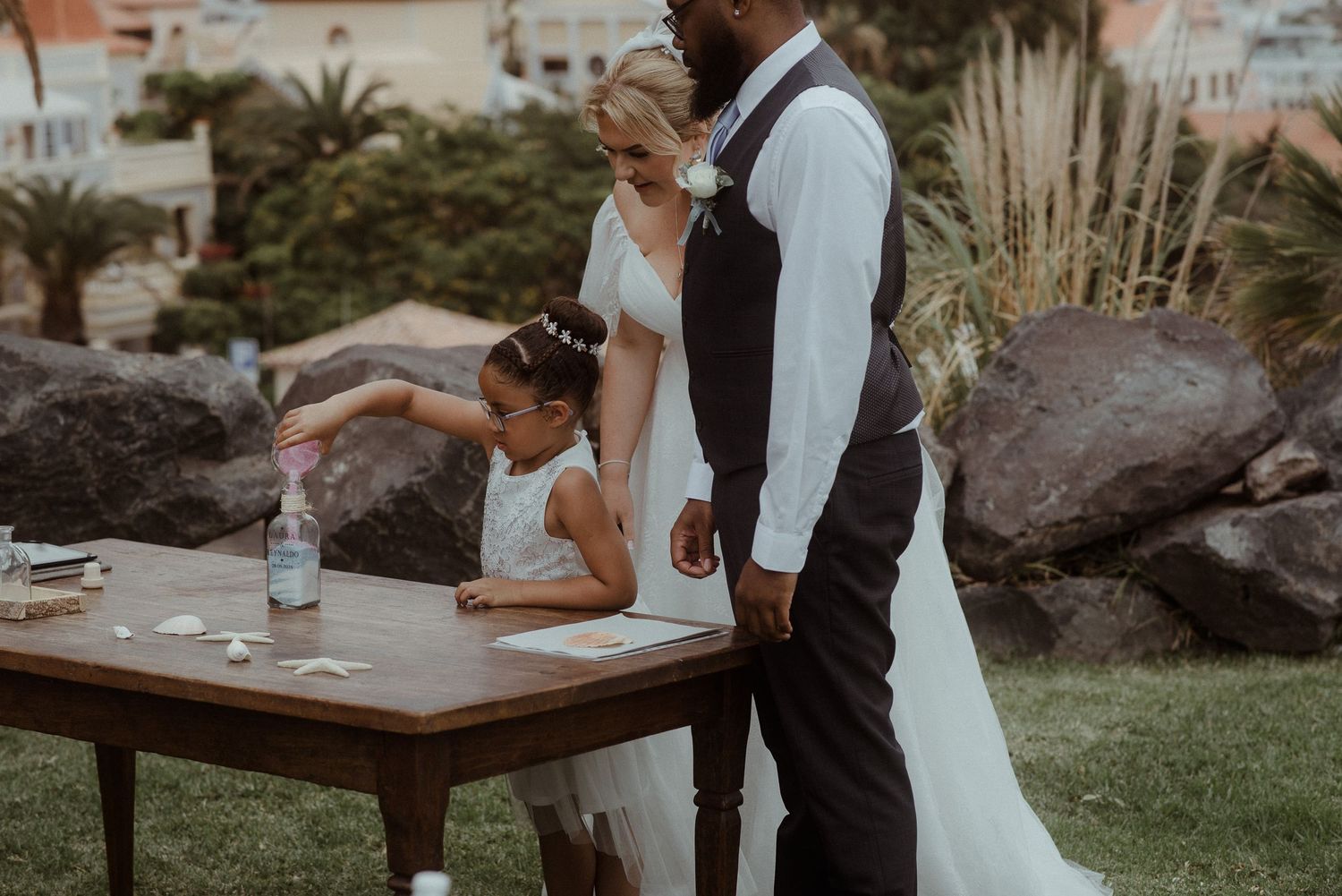 Wedding ceremony participants gathered around a wooden table during an outdoor ritual. Tenerife Wedding Photographer at Hotel Vincci
