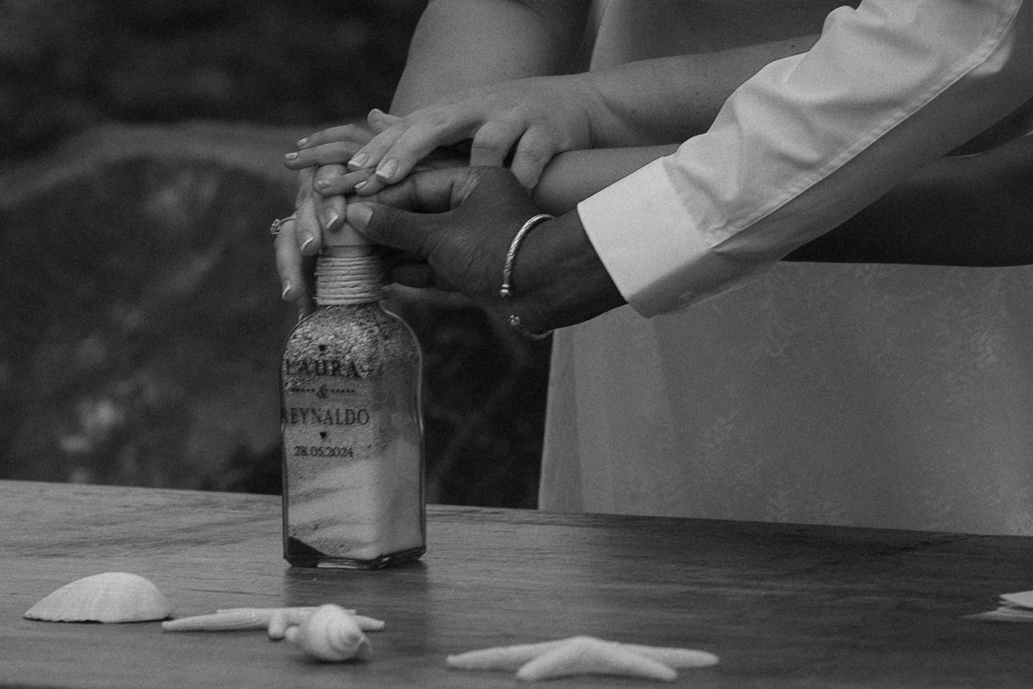 Close-up black and white photo of hands holding a bottle during a wedding ceremony. Tenerife Wedding Photographer at Hotel Vincci