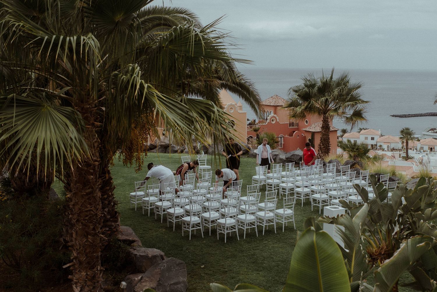 Outdoor wedding venue setup with white chairs and palm trees overlooking the ocean. Tenerife Wedding Photographer at Hotel Vincci