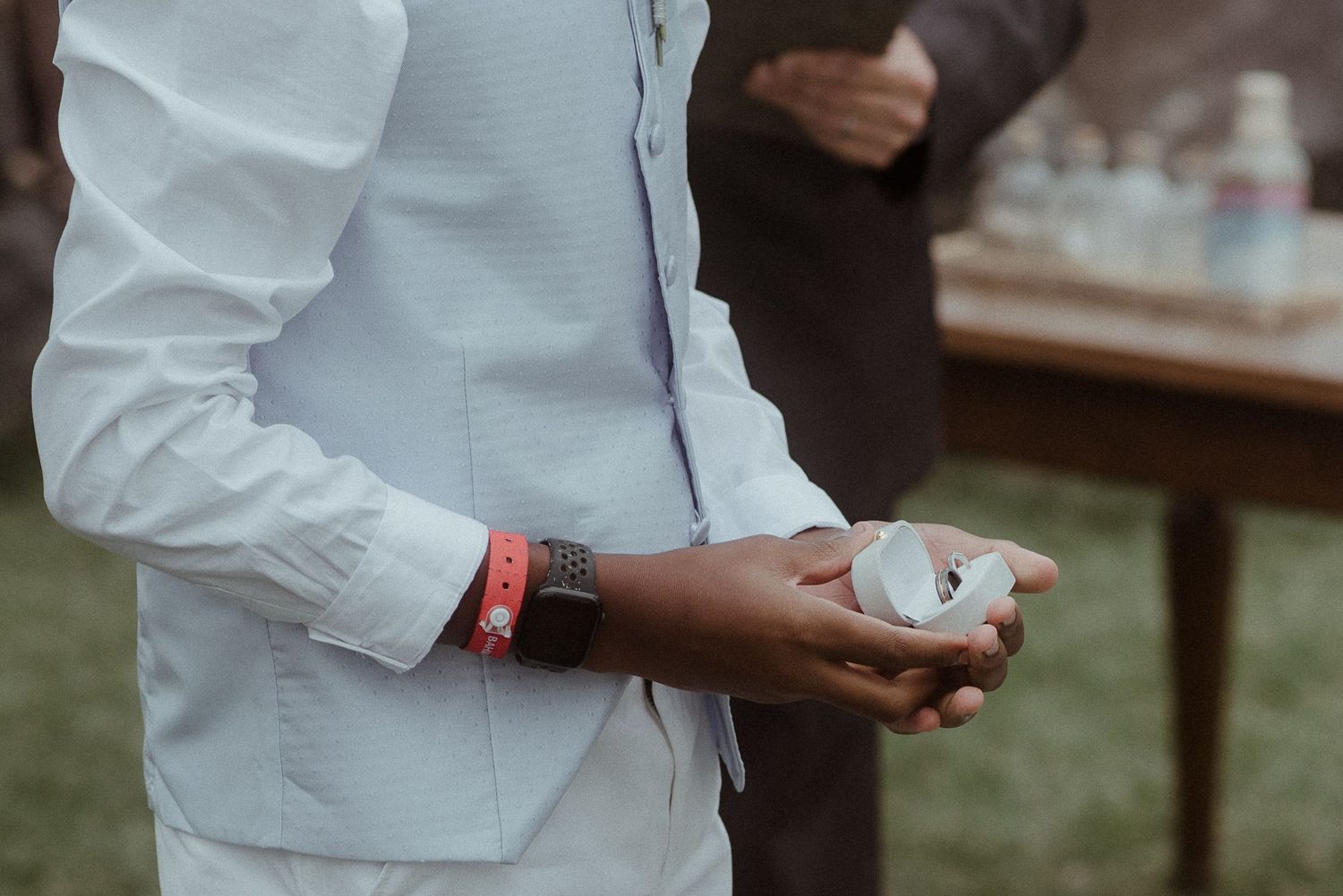 Close-up of hands holding small white object during wedding ceremony.