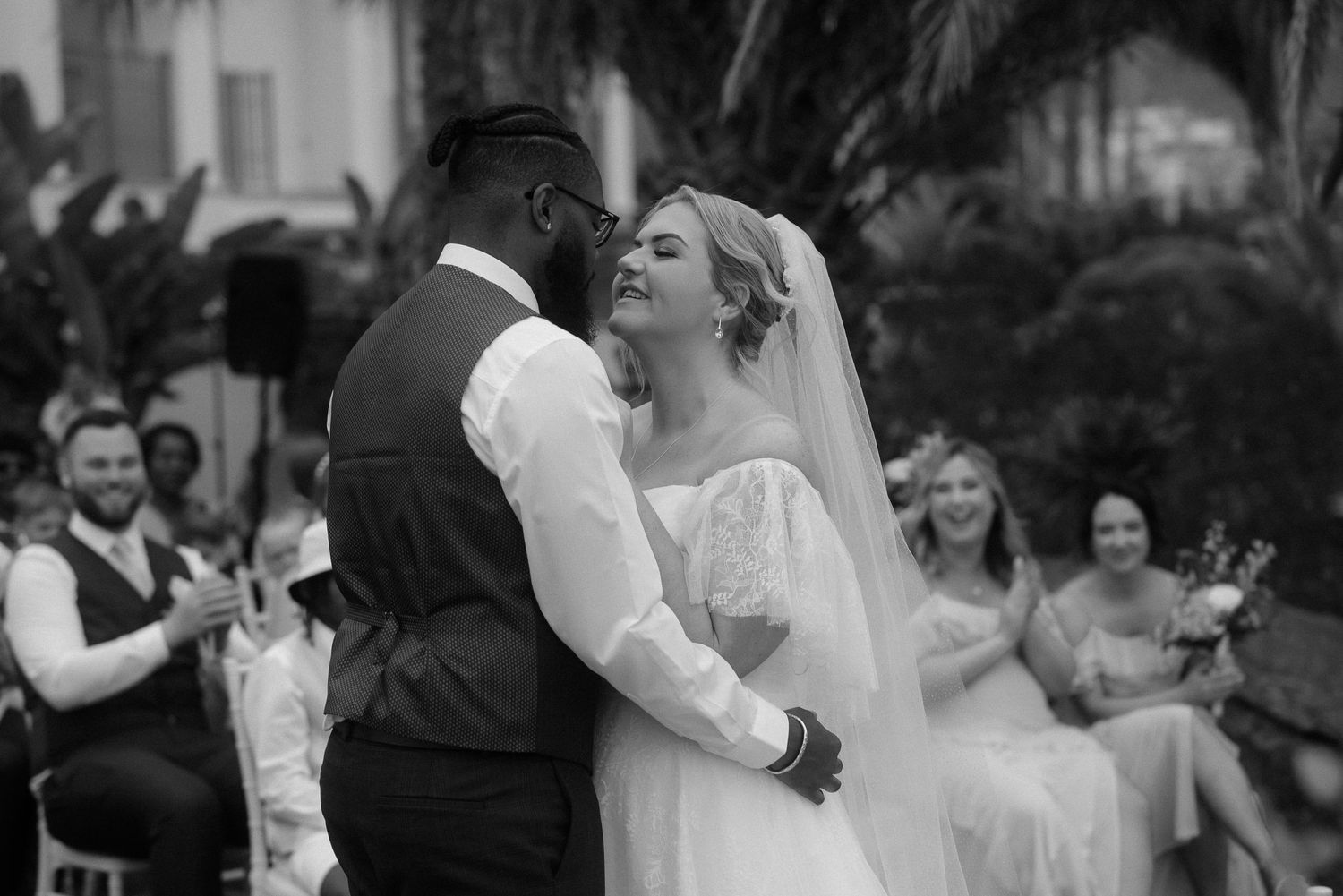 Black and white photo of joyful newlyweds during first dance at outdoor reception.