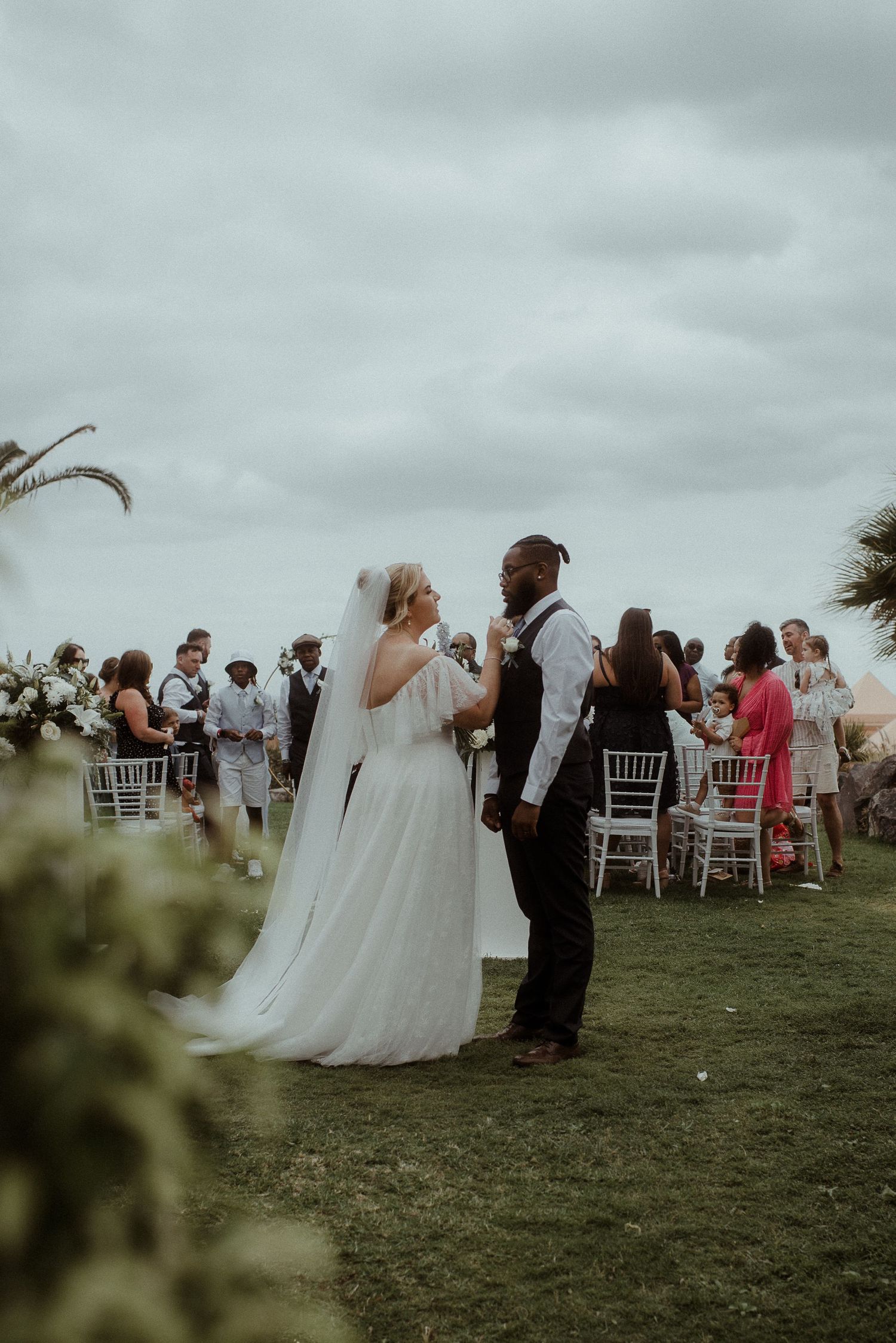 Intimate moment during outdoor wedding ceremony with palm trees and white decor.