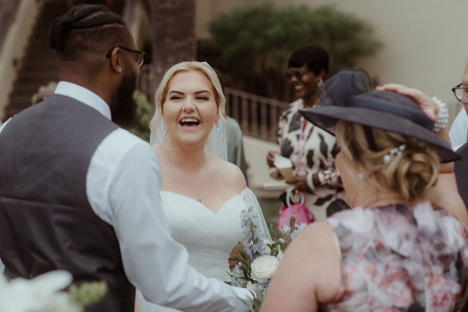 Wedding party guests share joyful laughter during an outdoor celebration.