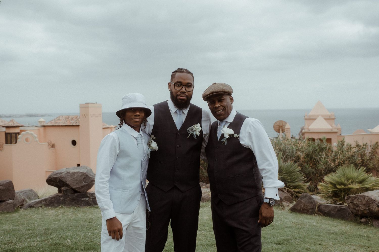 Three wedding party members in coordinated attire pose together on a scenic overlook.