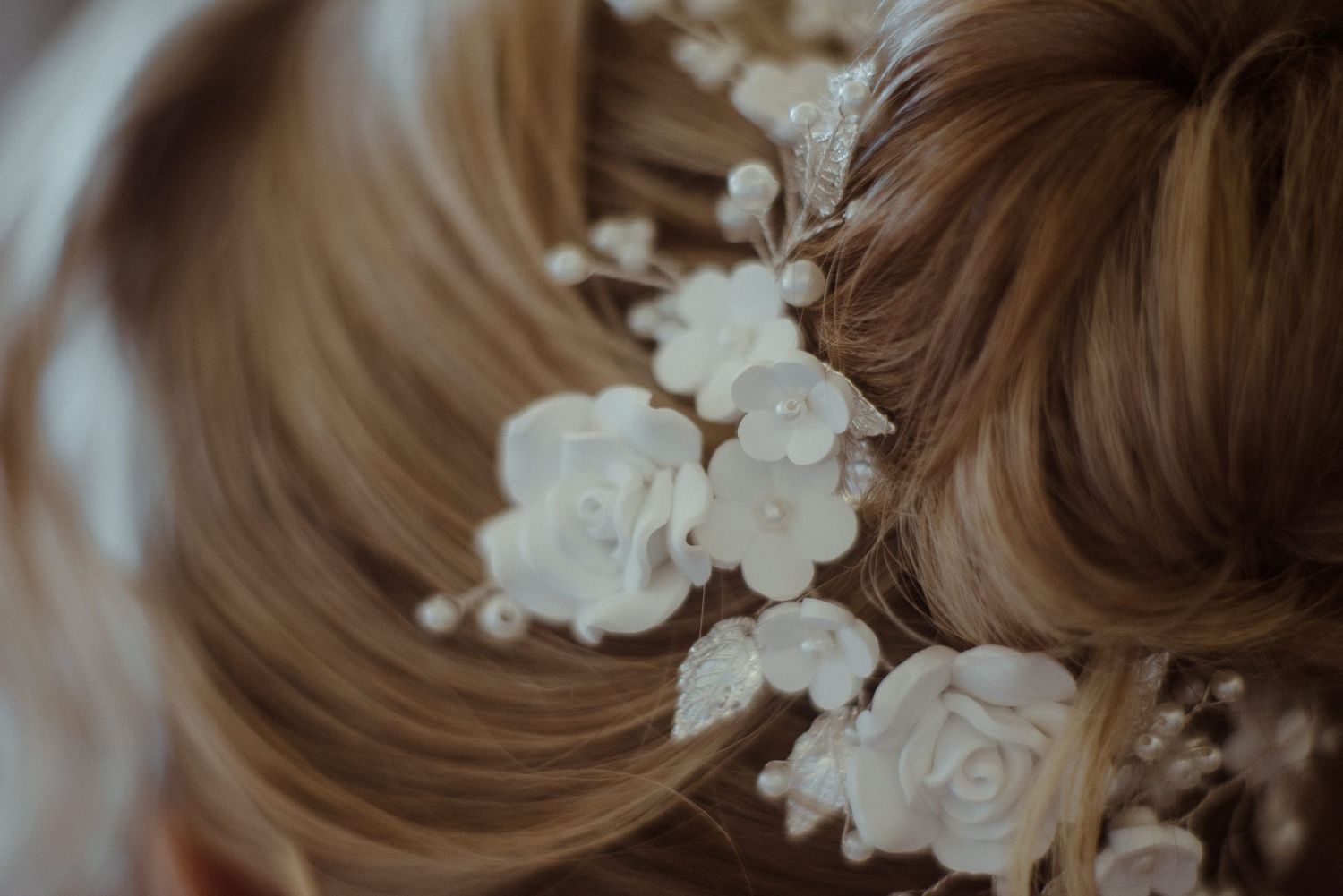 Delicate white floral hair accessories with roses and pearls nestled in styled hair.