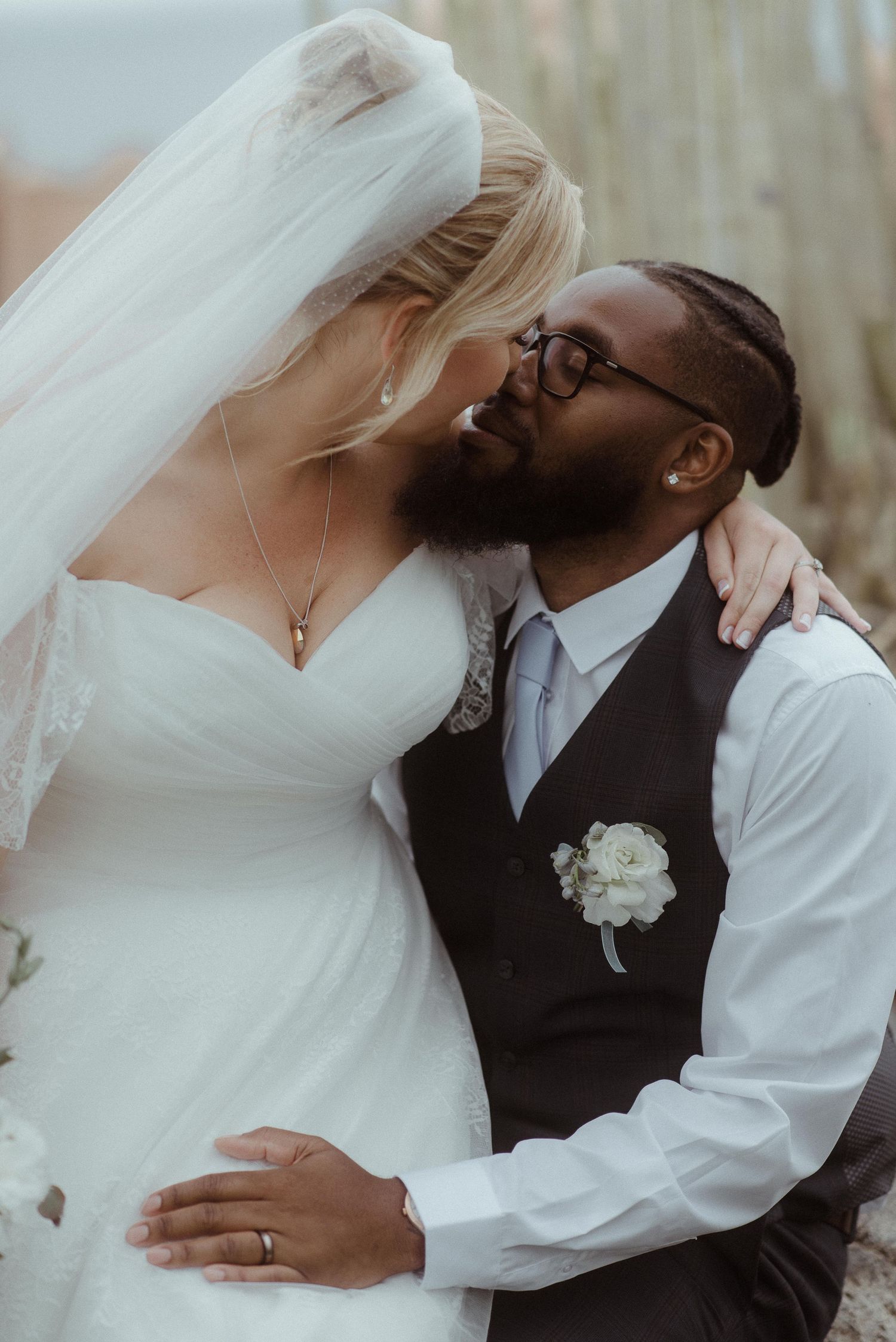 Romantic wedding portrait showing tender embrace against natural backdrop.