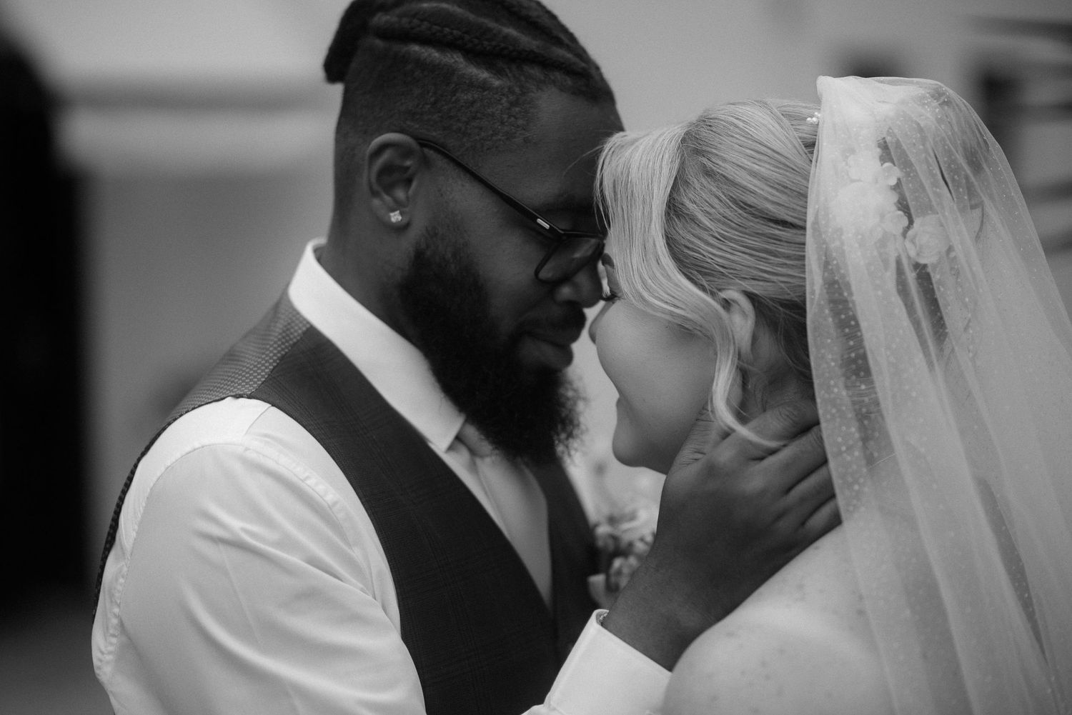 Black and white portrait captures emotional wedding moment between couple during ceremony.