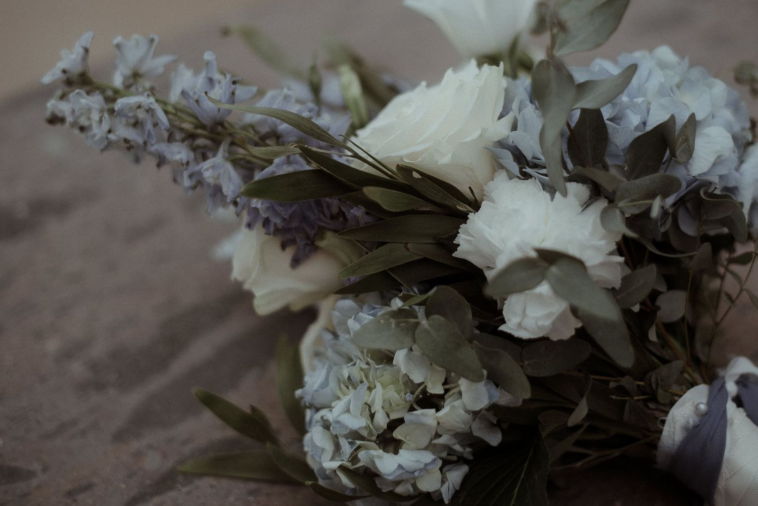 Close up detail of white and gray wedding bouquet with delicate floral arrangement.
