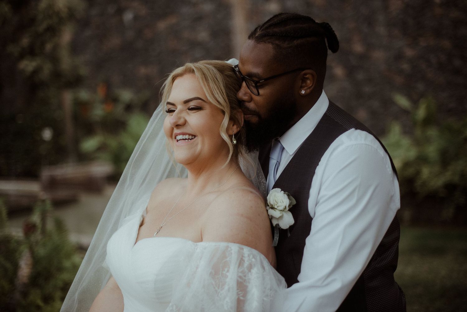 A newlywed couple sharing an intimate moment outdoors during their wedding photoshoot.