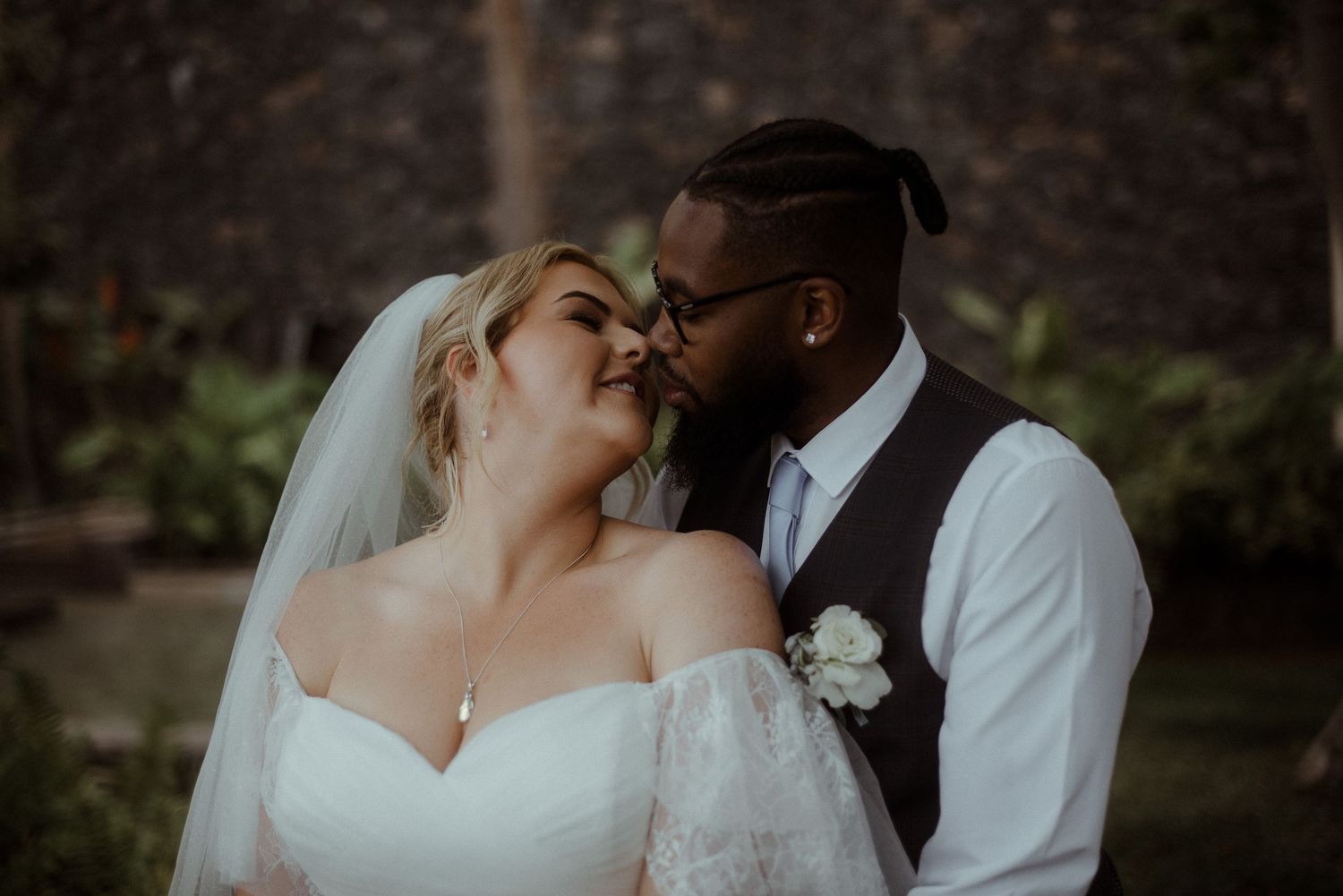 A romantic wedding moment captured between the bride in white and groom in a vest.