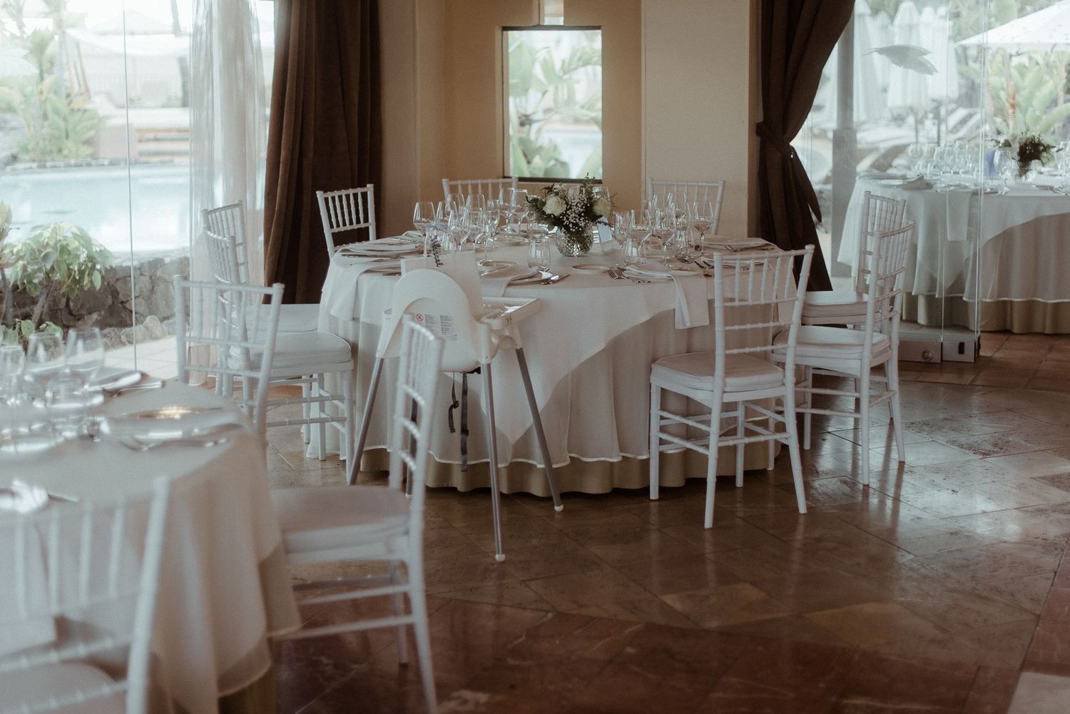 Elegant wedding reception room with white chiavari chairs and round tables.