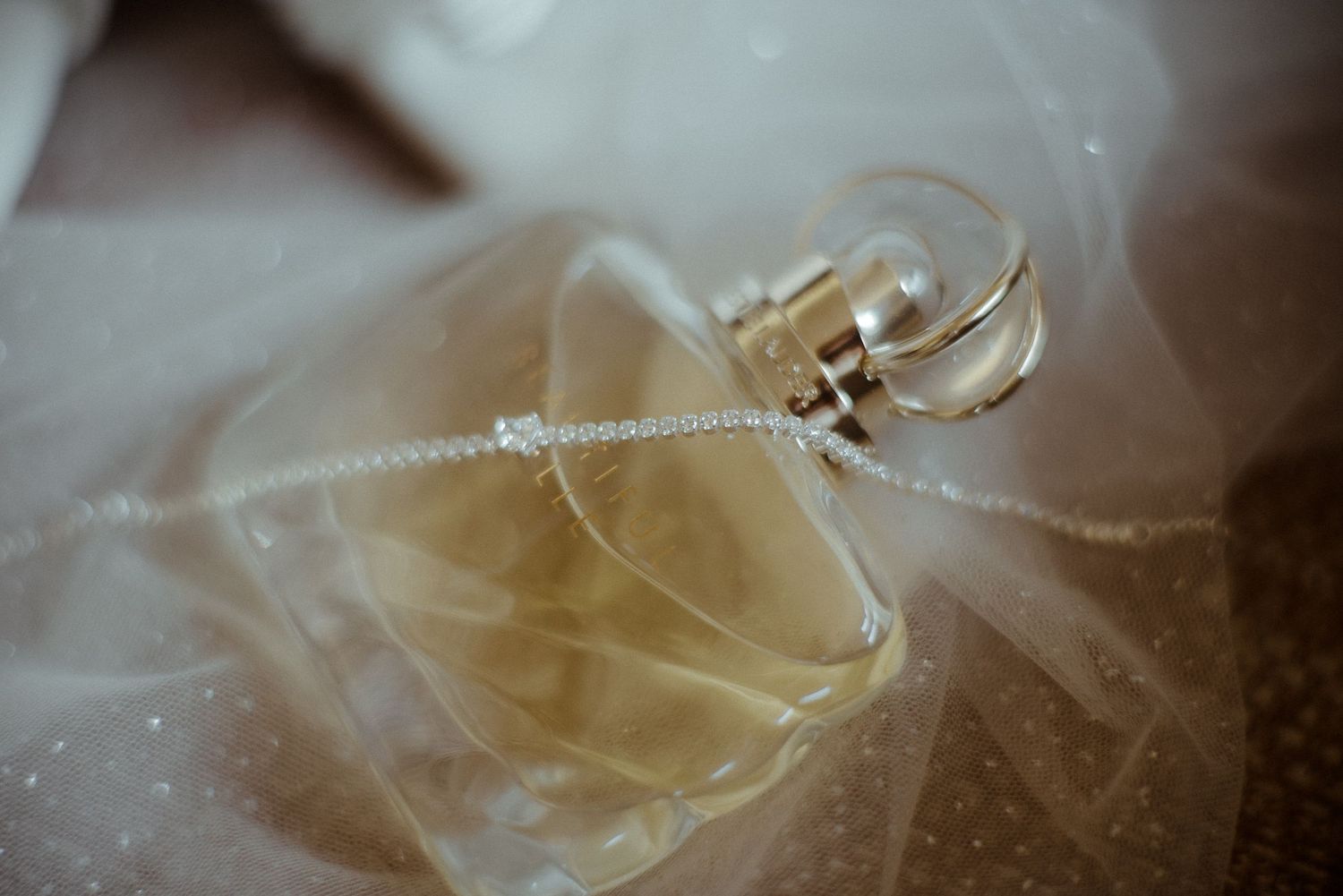 Wedding rings nestled in delicate white tulle veil with soft focus.