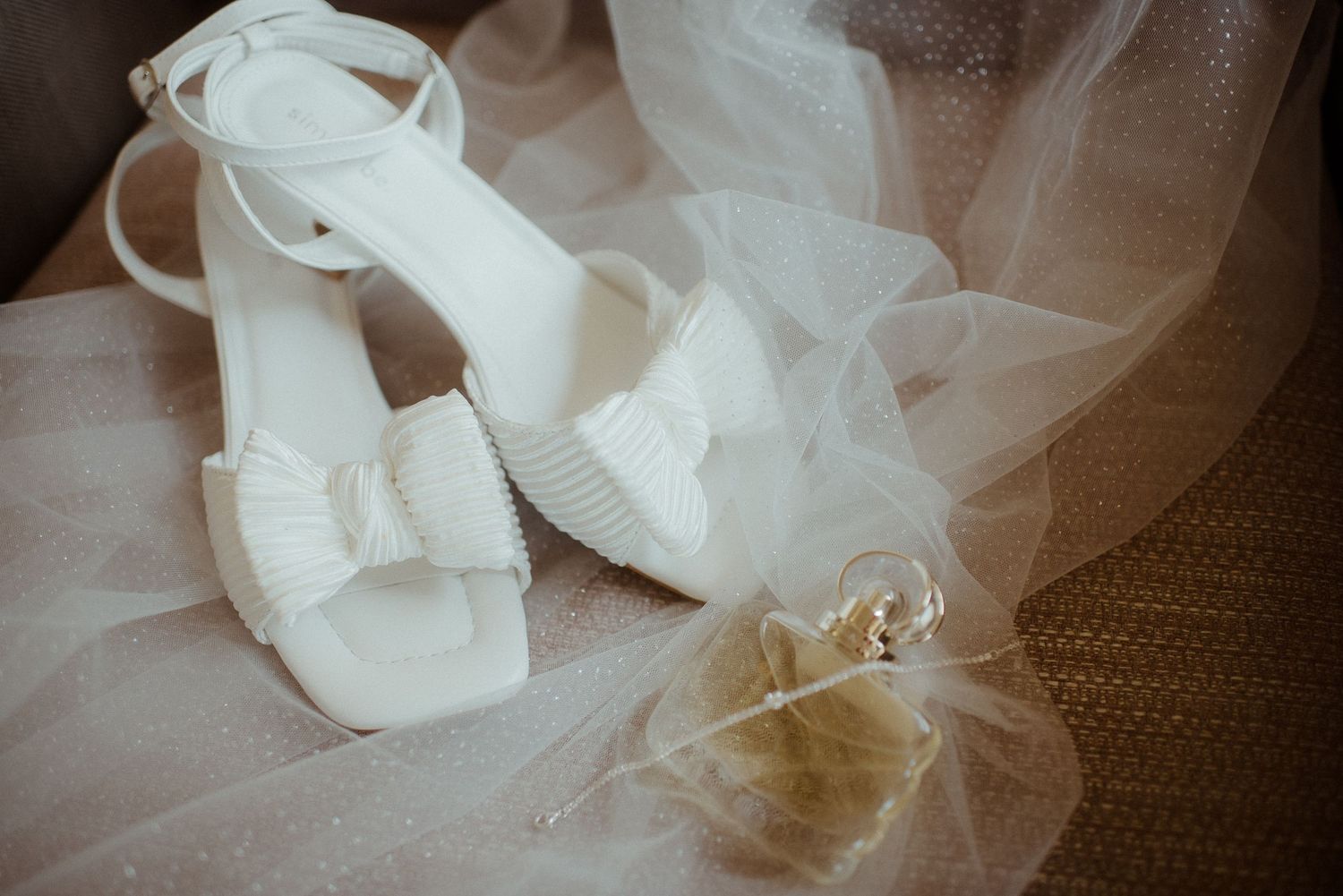 White bridal shoes and wedding rings arranged with flowing tulle veil. Tenerife Wedding Photographer at Hotel Vincci La Plantación del Sur