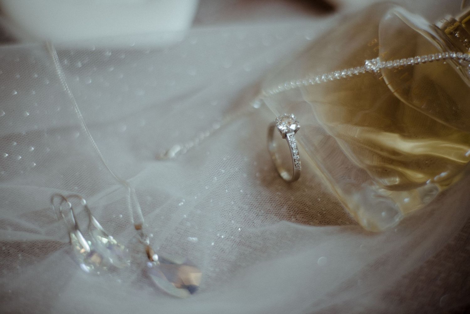 Crystal wedding accessories and jewelry photographed through ethereal veil material.