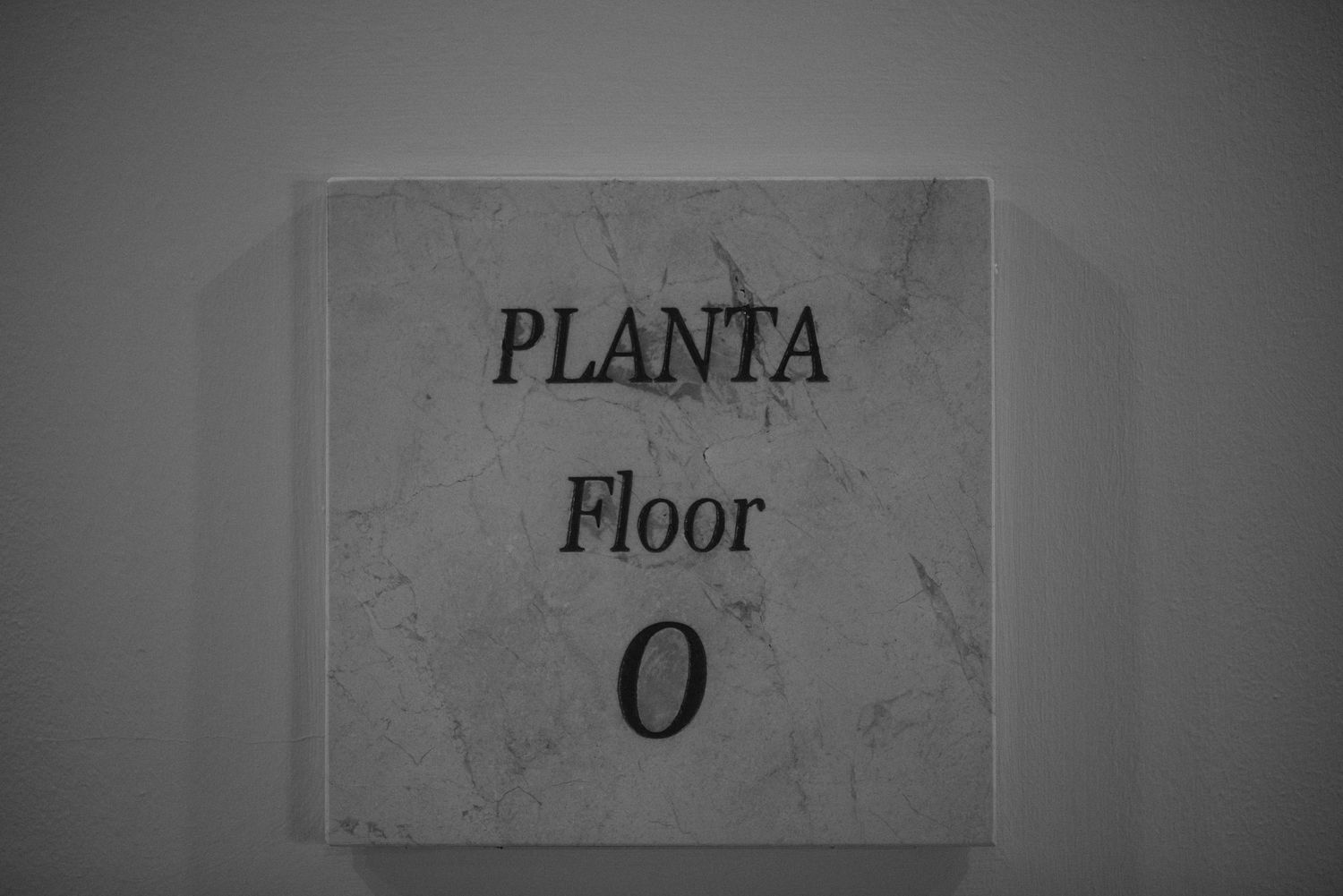Black and white sign reading 'PLANTA Floor 0' mounted on a wall.