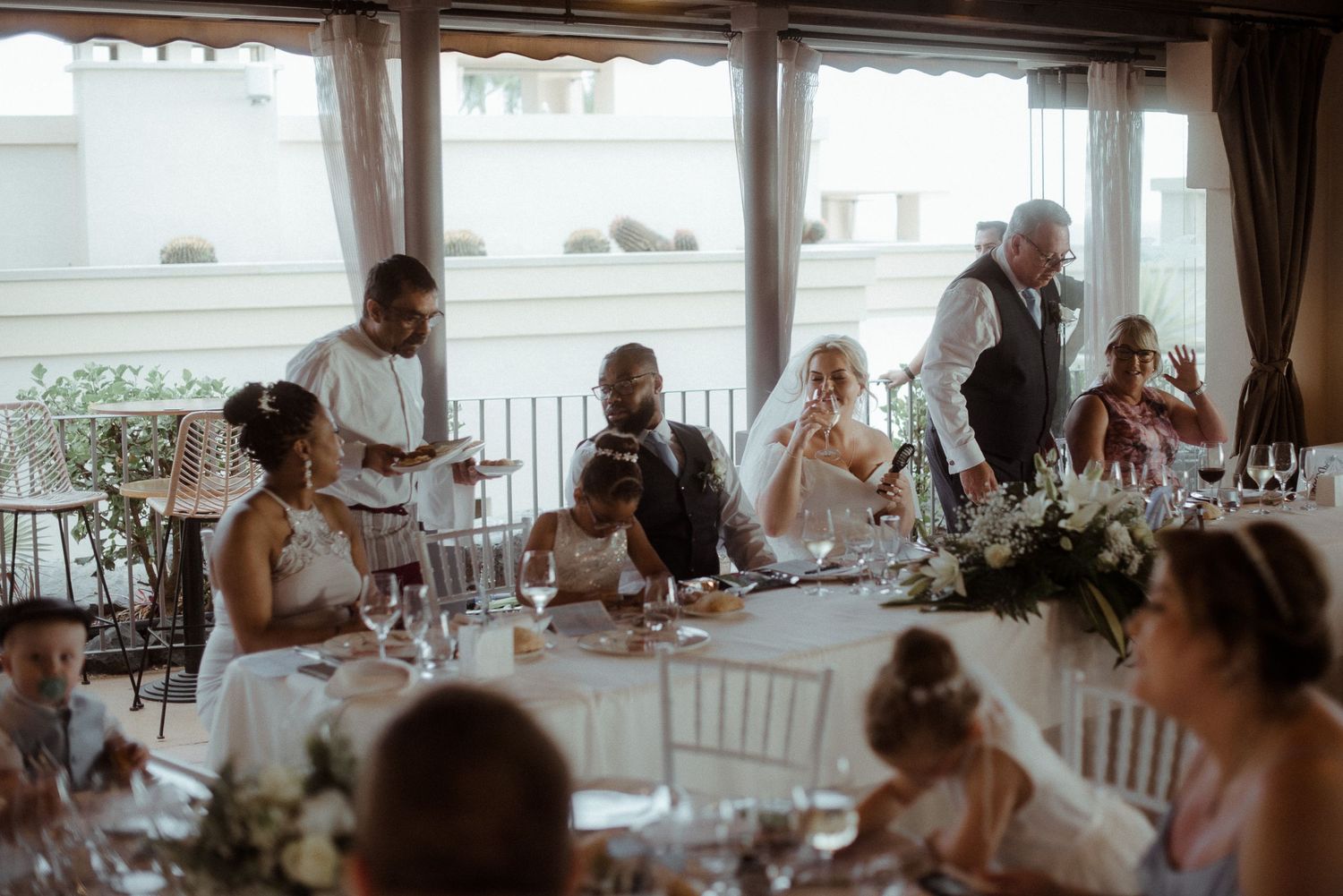Wedding guests gather around elegantly decorated tables for the reception dinner.