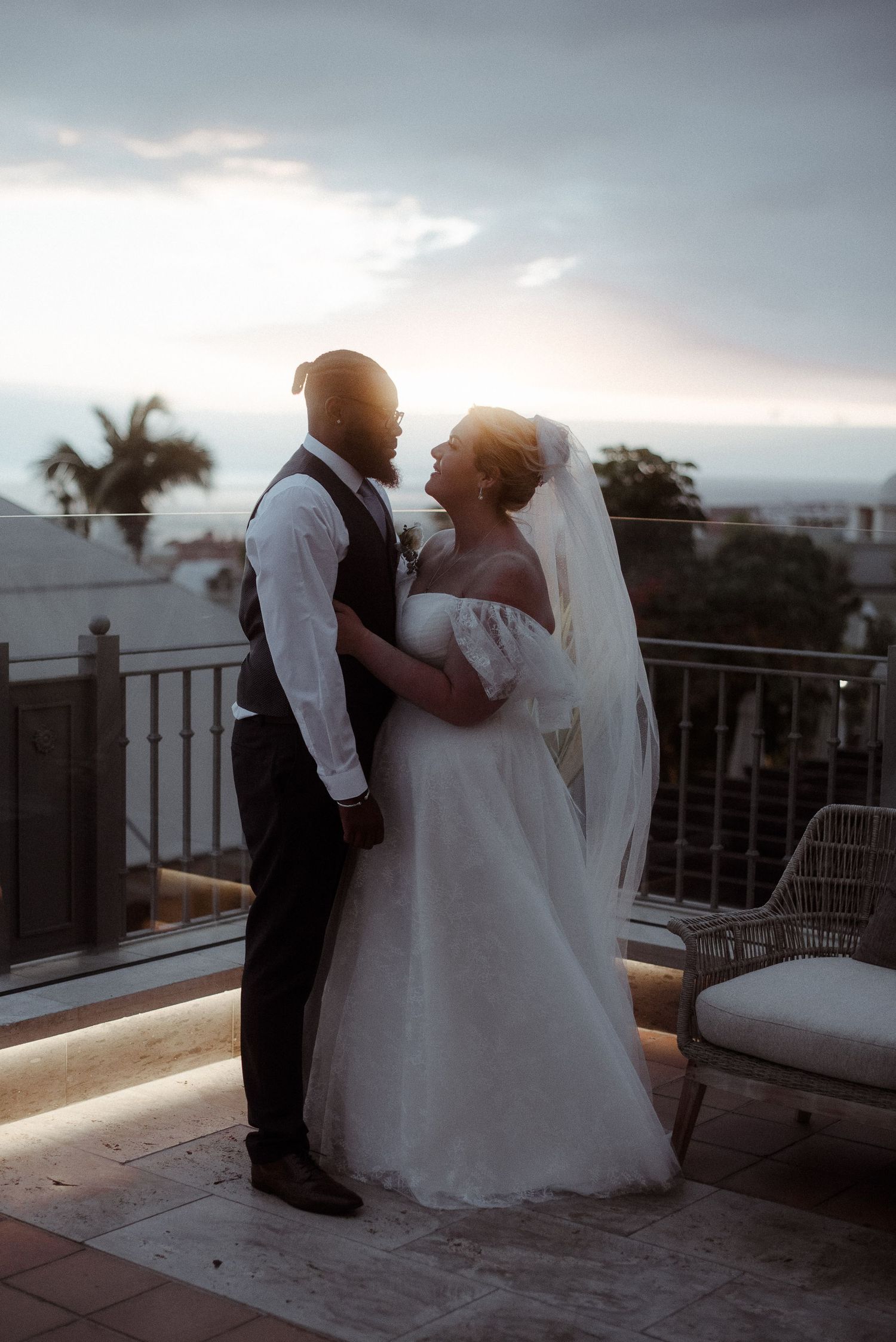 A couple shares an intimate moment on a balcony at sunset.
