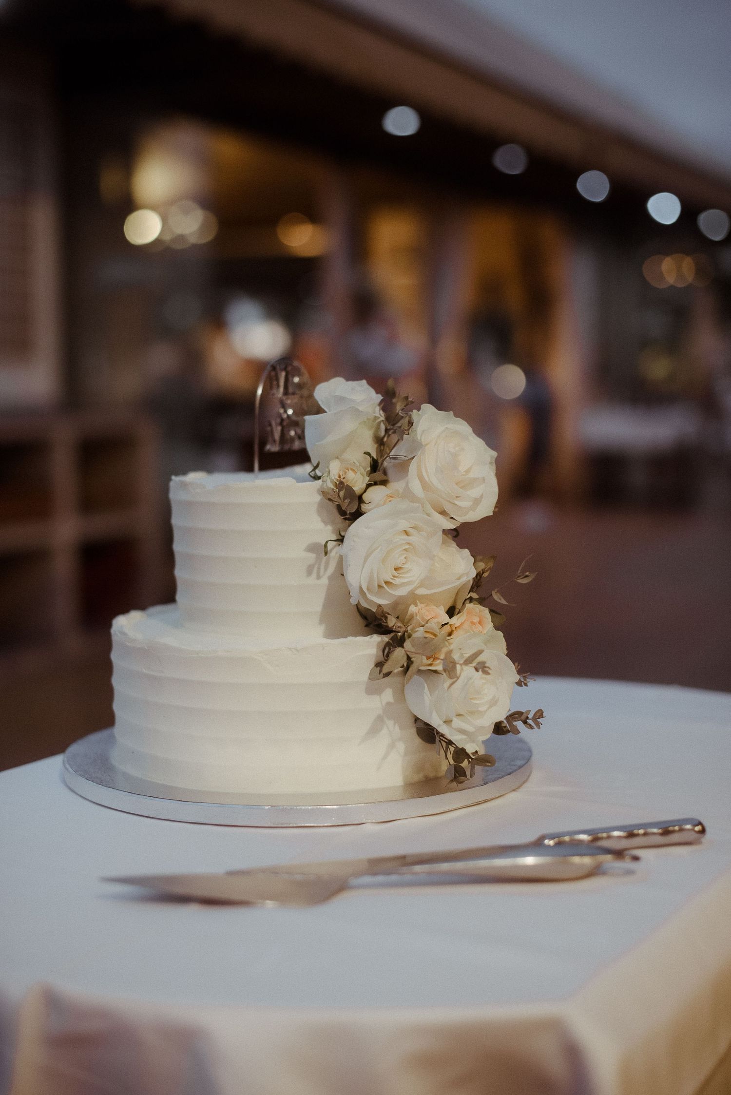 Elegant white wedding cake decorated with fresh roses on display.