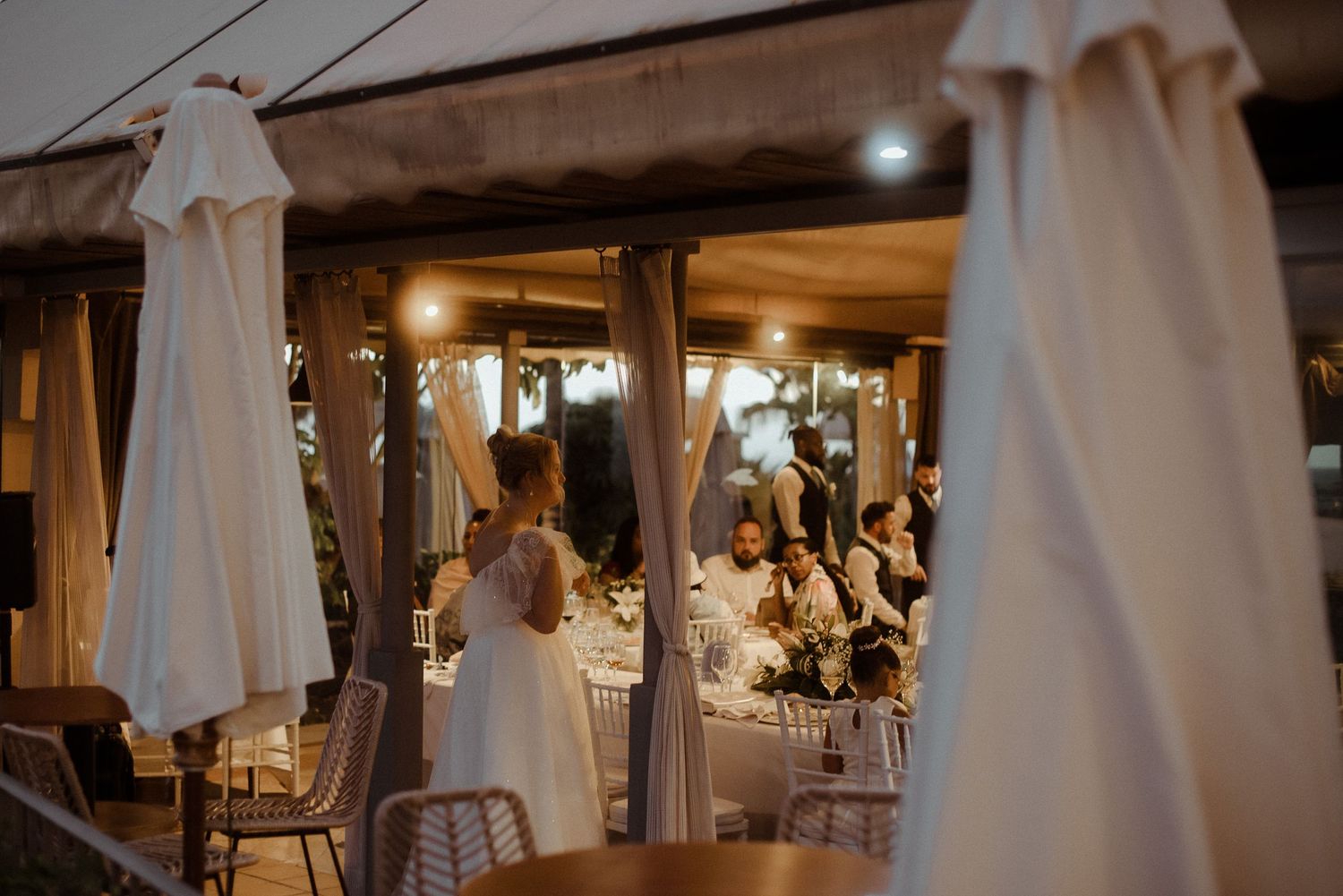 Elegant wedding reception venue with white drapes and soft lighting creating a romantic atmosphere.