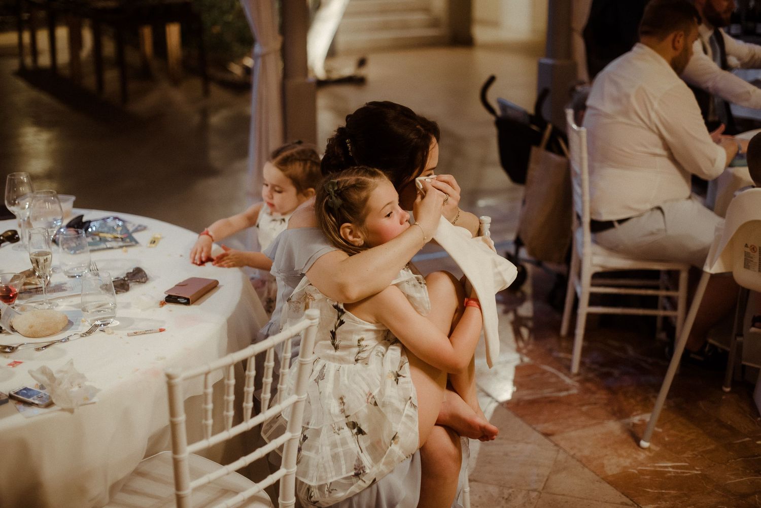 Young children sharing a sweet moment at a wedding reception table.