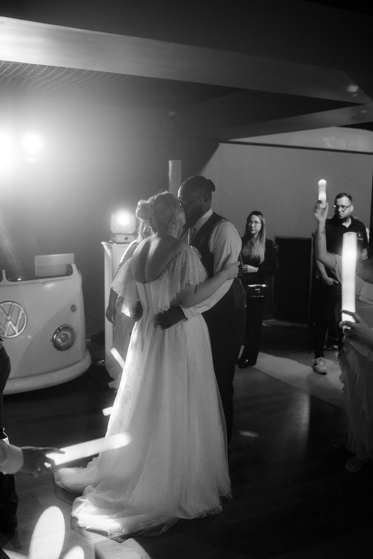 A romantic first dance at a wedding reception with an illuminated vintage VW bus in the background.