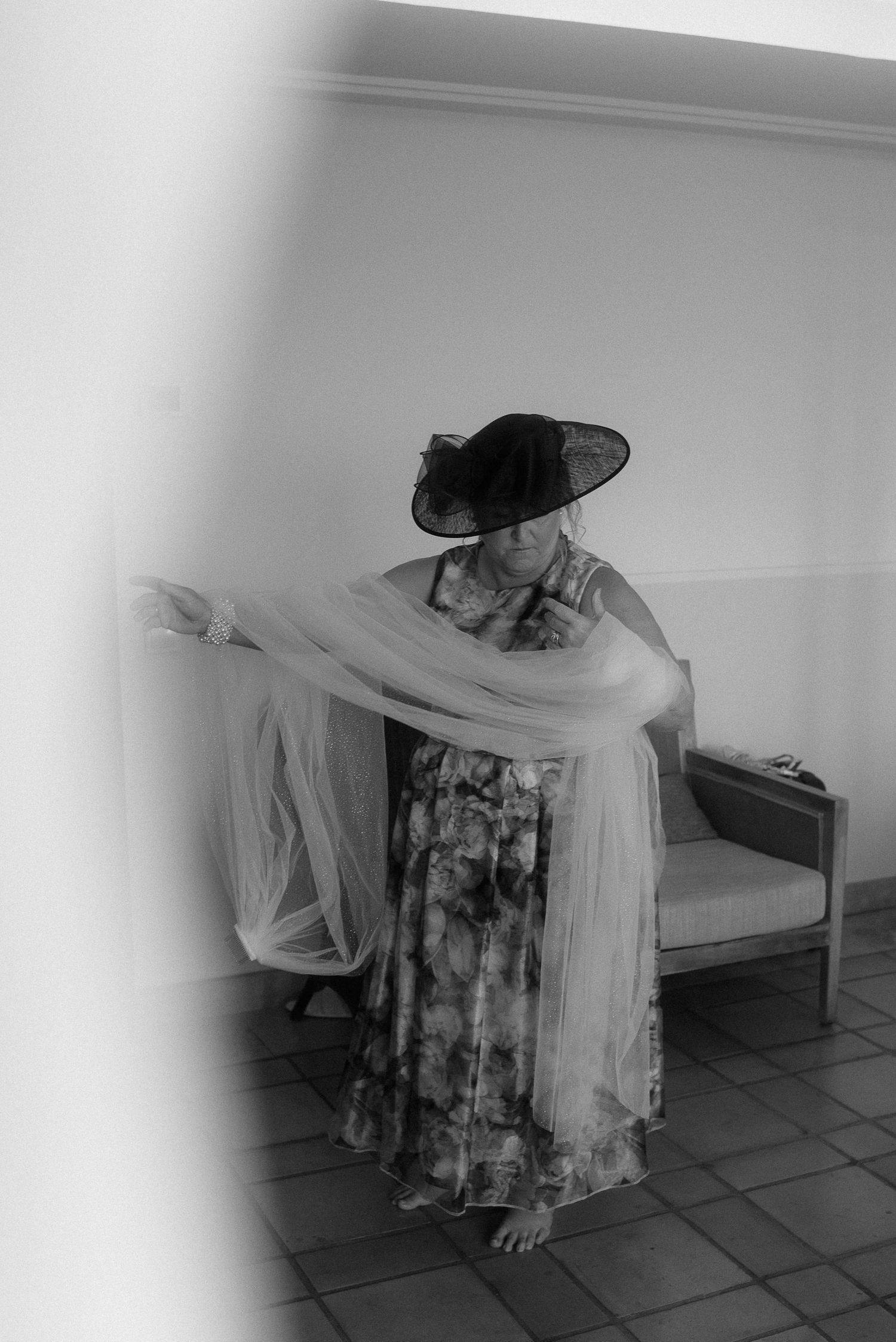 Person in vintage dress and hat draped in flowing fabric posing artistically.