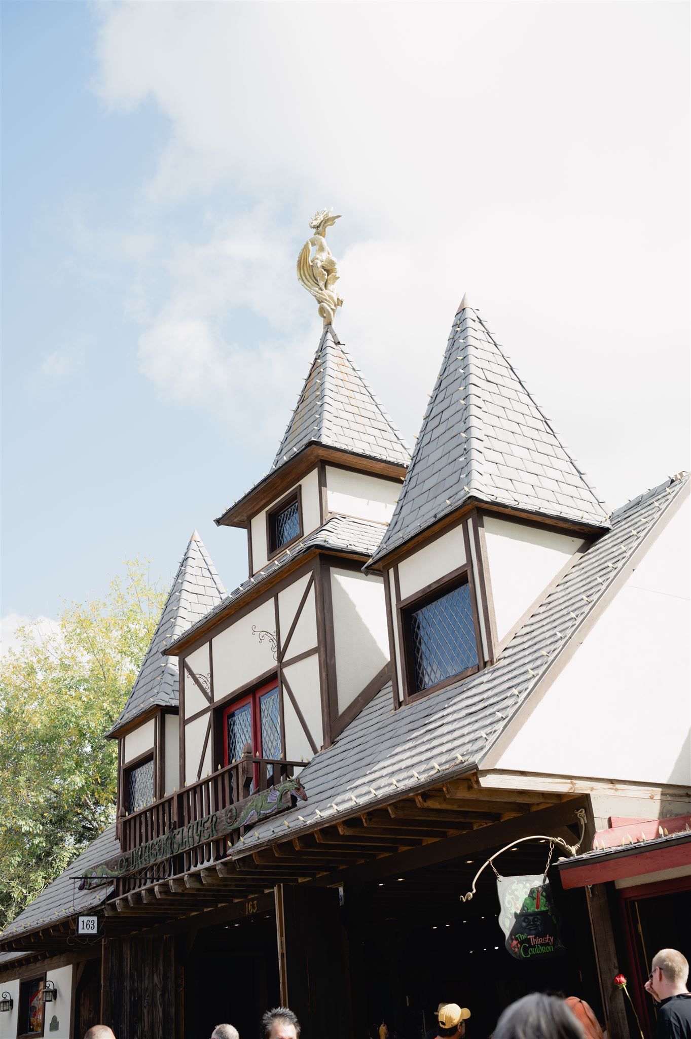 Medieval-style architecture featuring multiple pointed spires and Tudor-style buildings with white and brown exteriors at a shopping area.