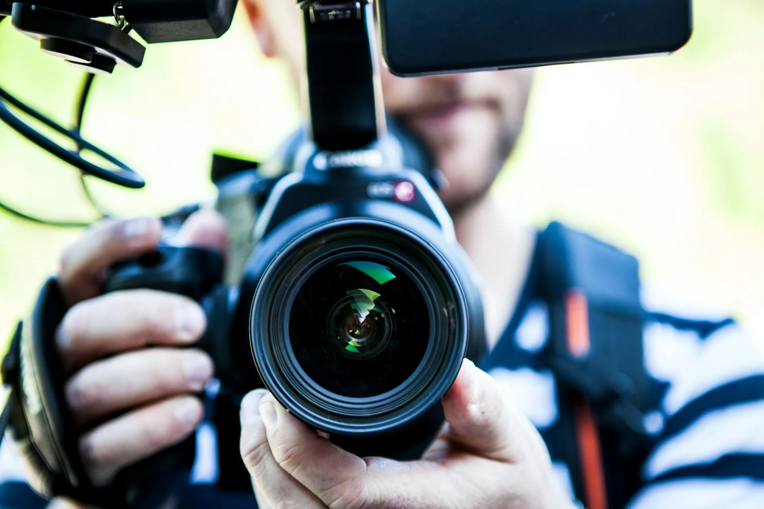 Professional camera with telephoto lens being operated in closeup outdoor shot.